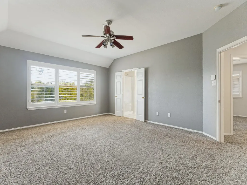 Carpeted room featuring a vaulted ceiling and a ceiling fan