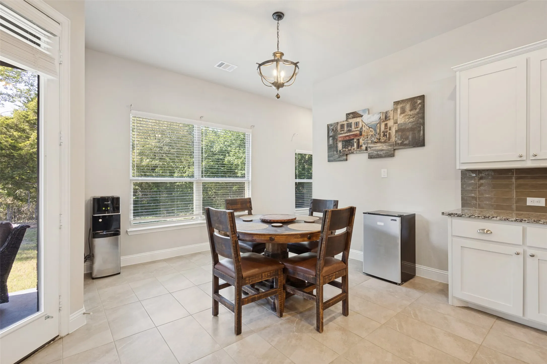 White cabinetry, stone-finish countertops, tiled backsplash, large windows, and tiled flooring