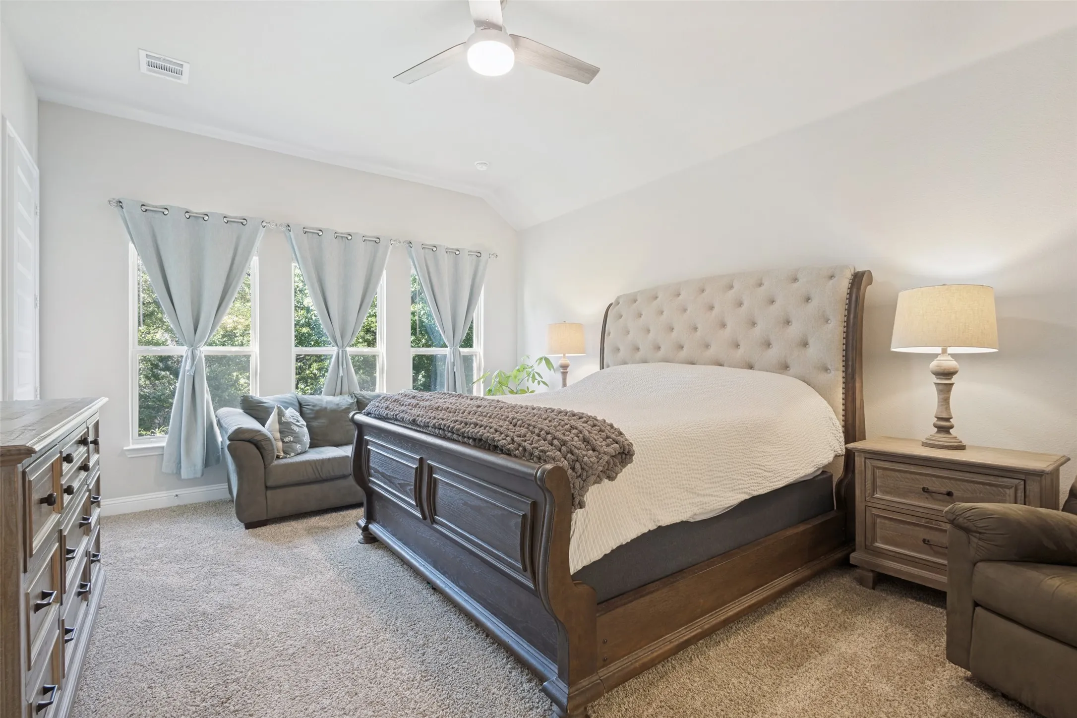 Vaulted ceiling with a ceiling fan, three large windows, and wall-to-wall carpeting
