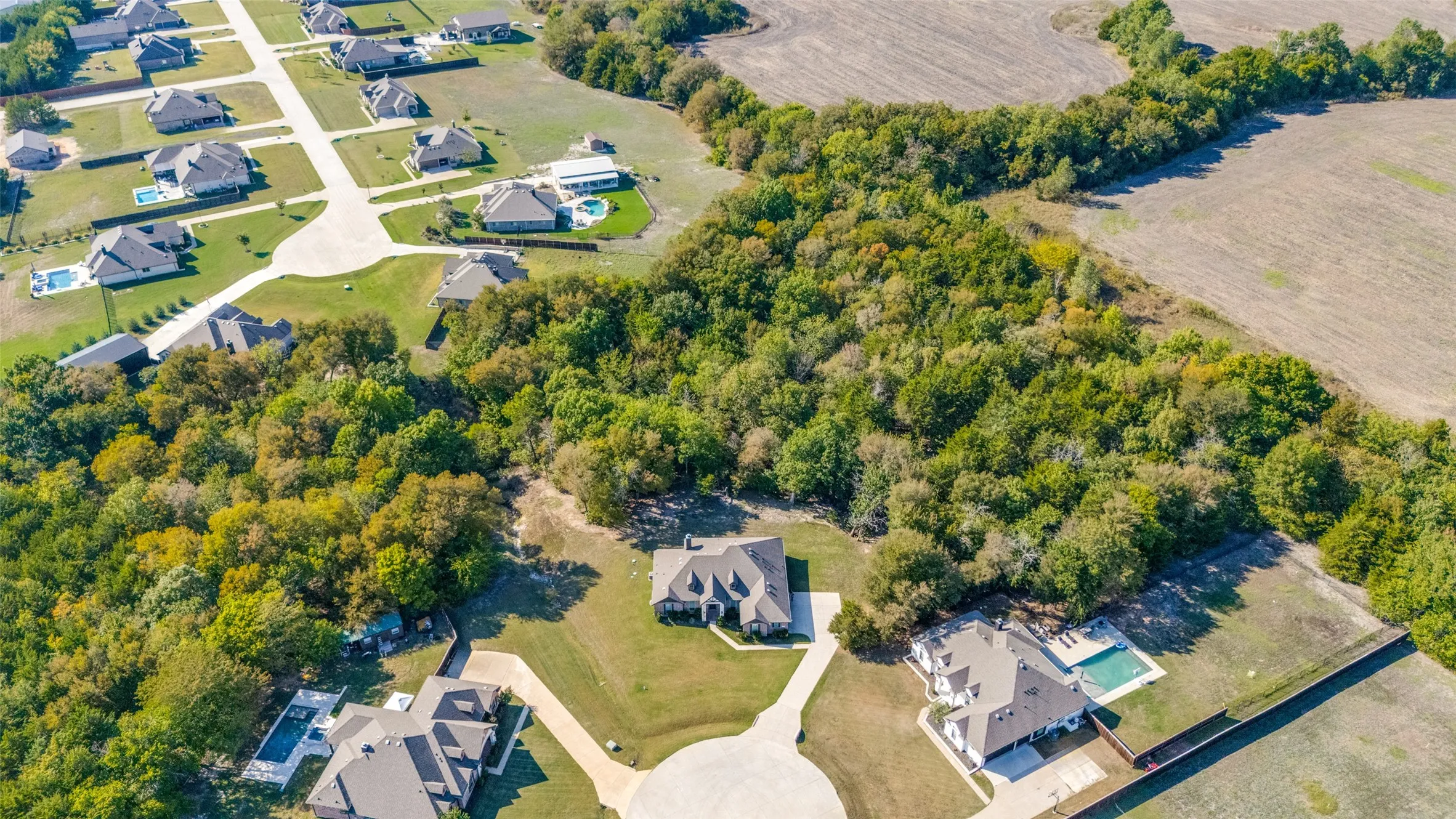 Expansive residential development with mature trees, established properties, and paved roadways