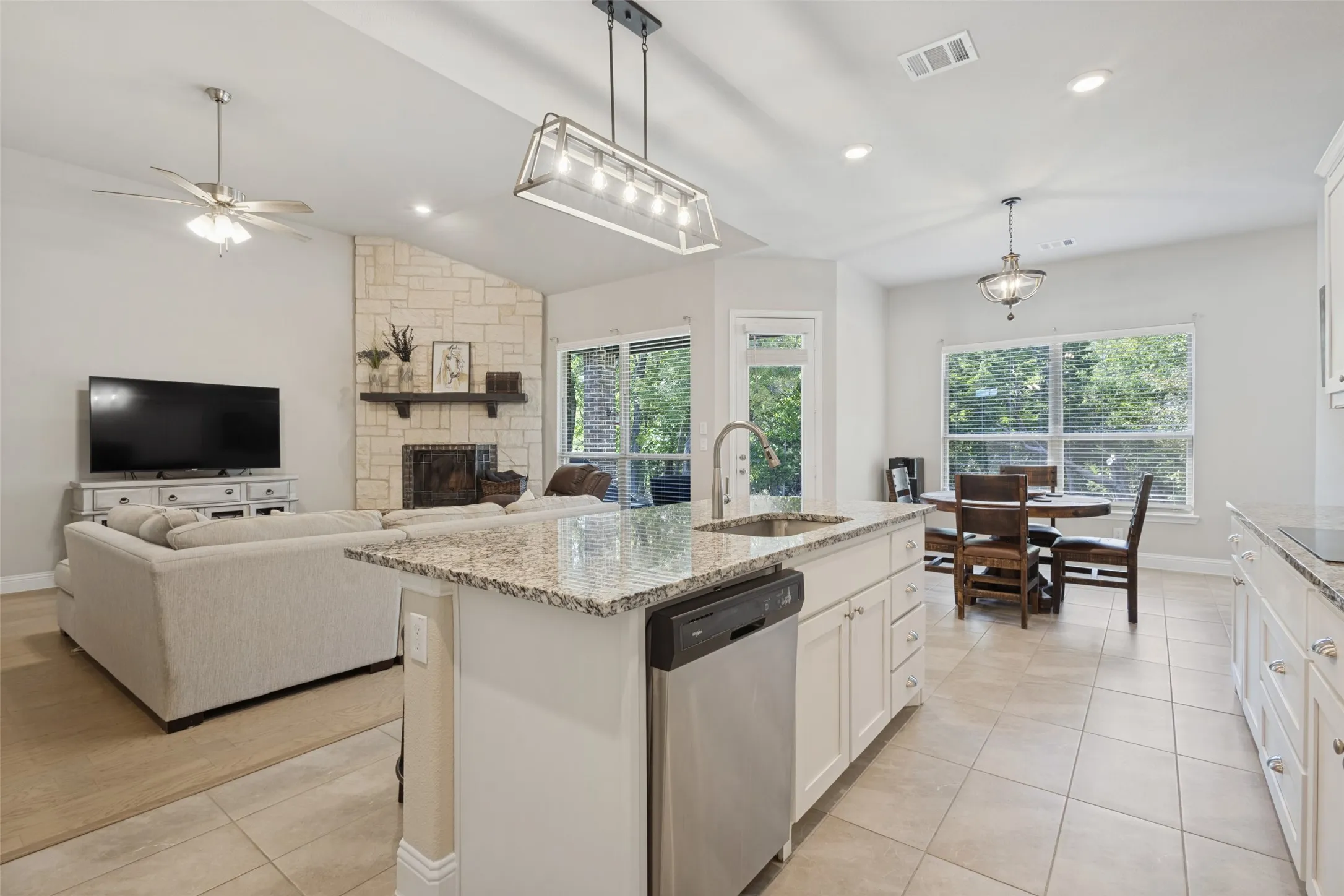 Kitchen island with granite countertop, stainless steel sink, and built-in dishwasher