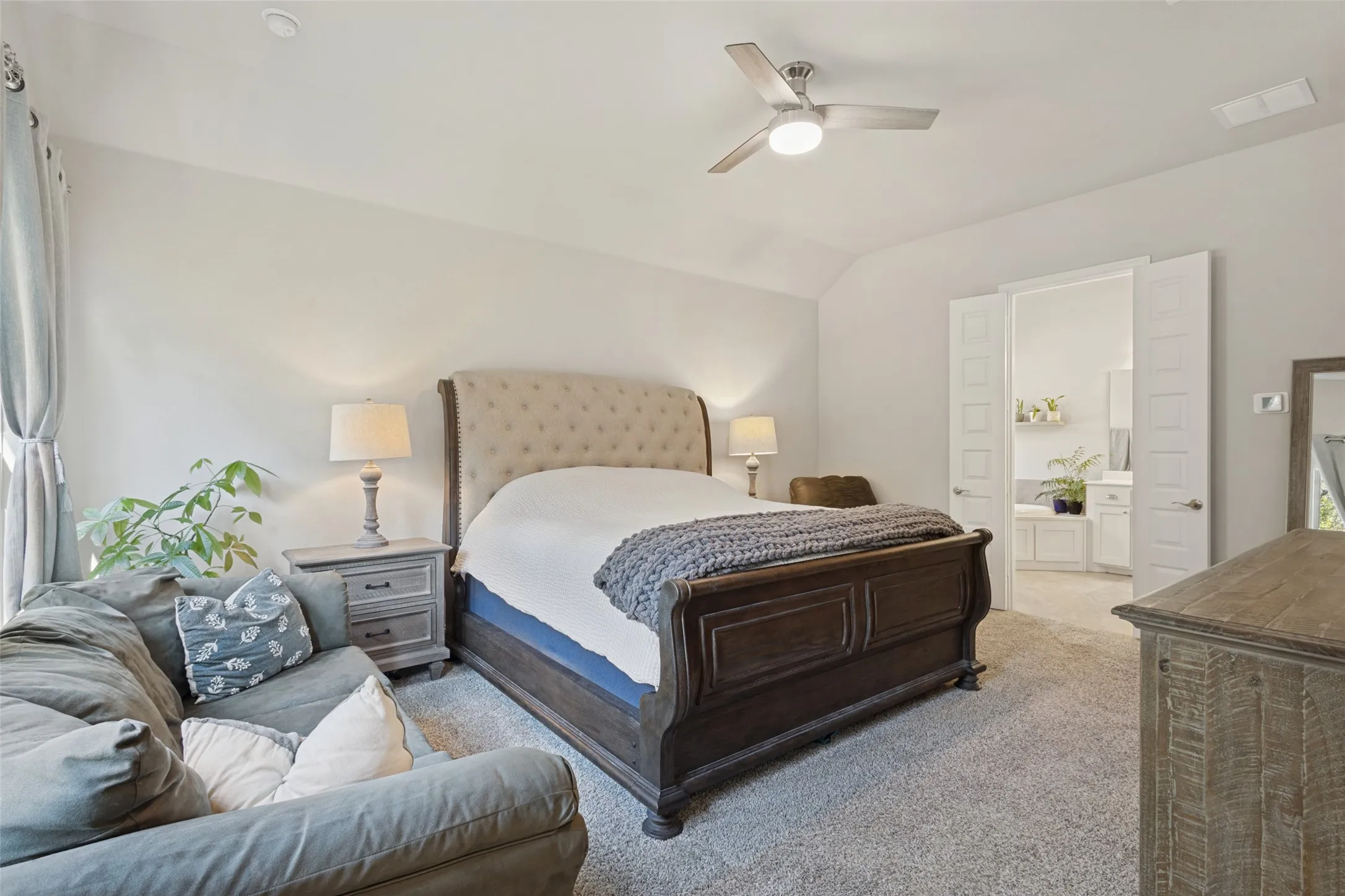 Vaulted ceiling, ceiling fan, neutral wall paint, carpet flooring, and double doors