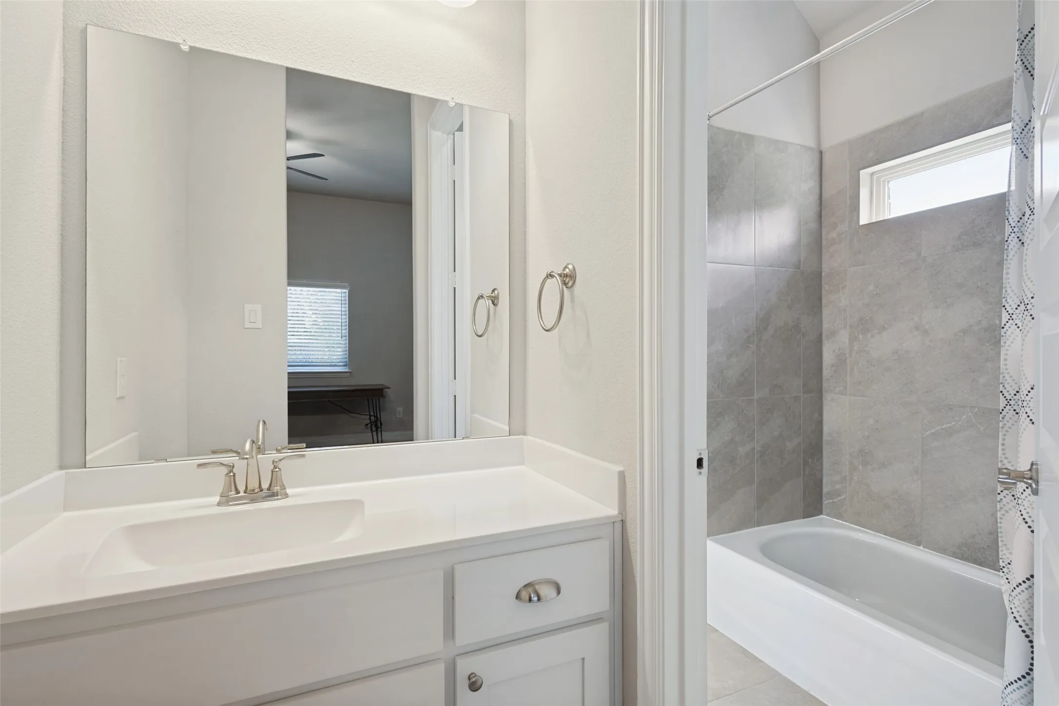 White vanity with brushed nickel hardware, integrated sink, and a large mirror
