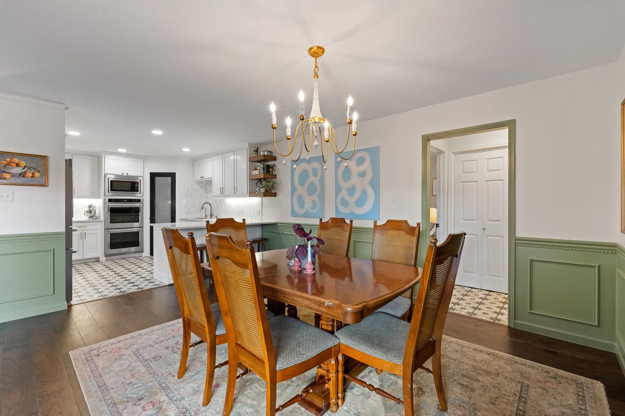 Wood flooring, accent wainscoting, and a gold-finish chandelier