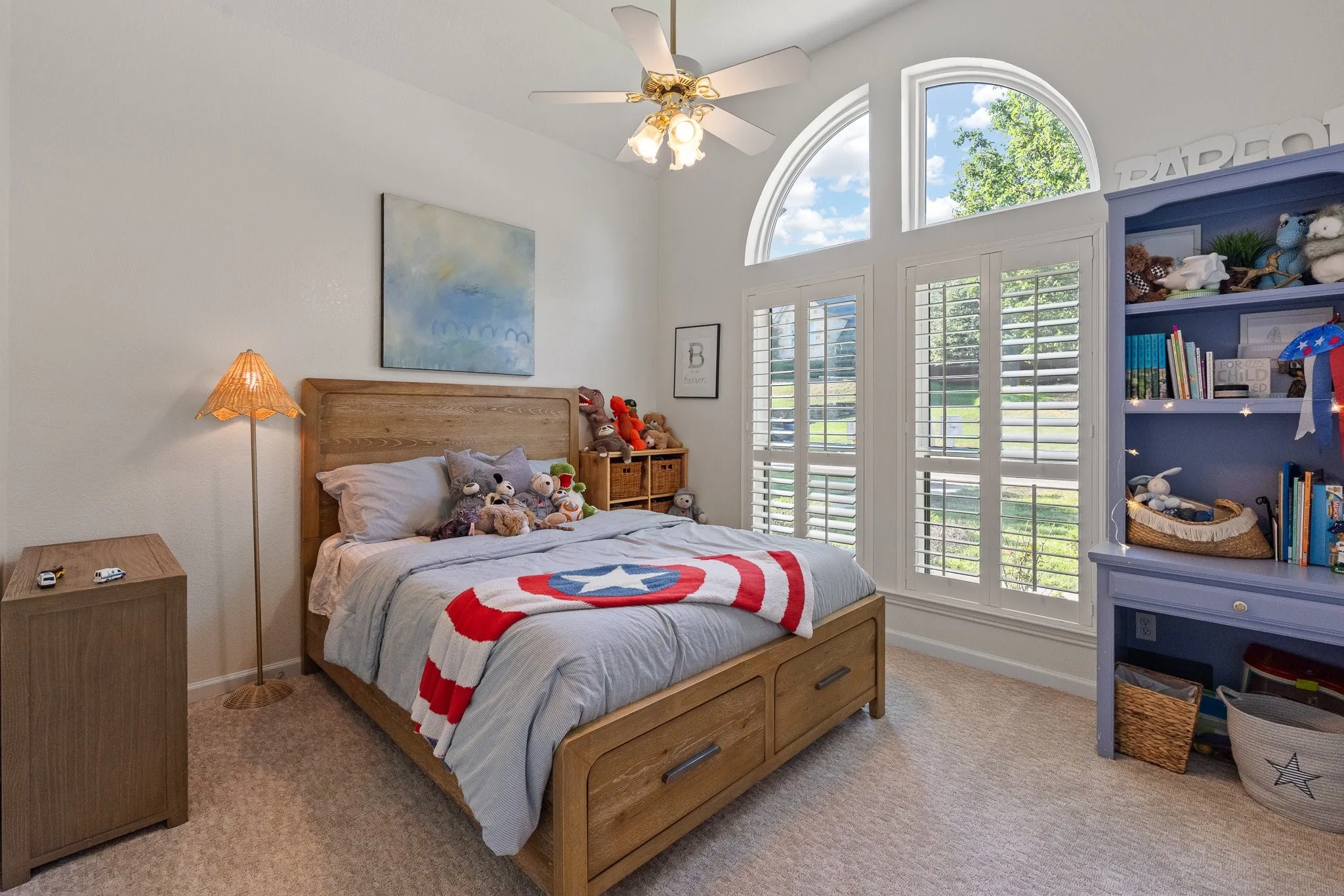 Arched windows with plantation shutters with built-in storage, and a ceiling fan