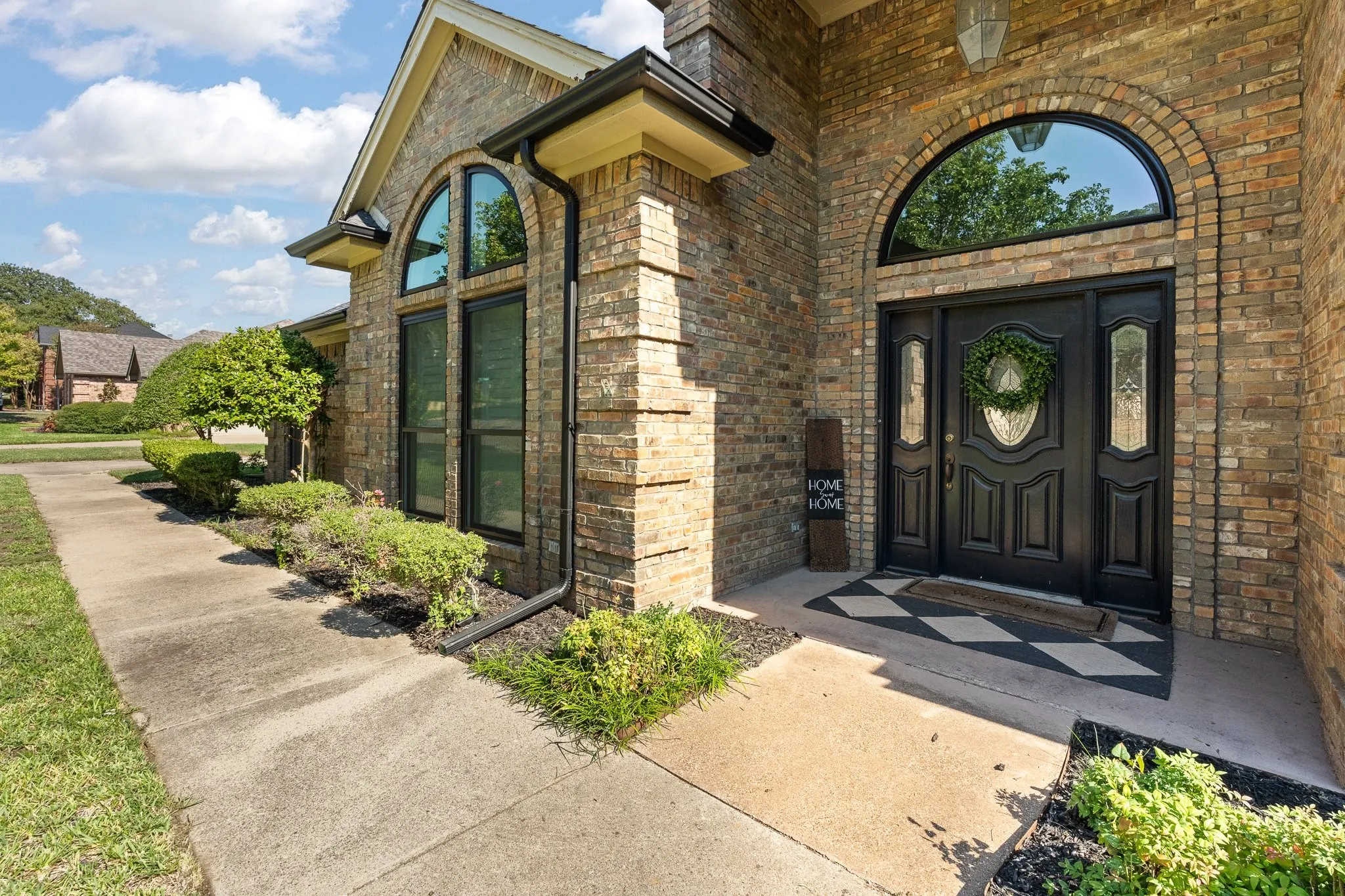 Elegant brick facade with arched transom windows and black multi-panel entry door