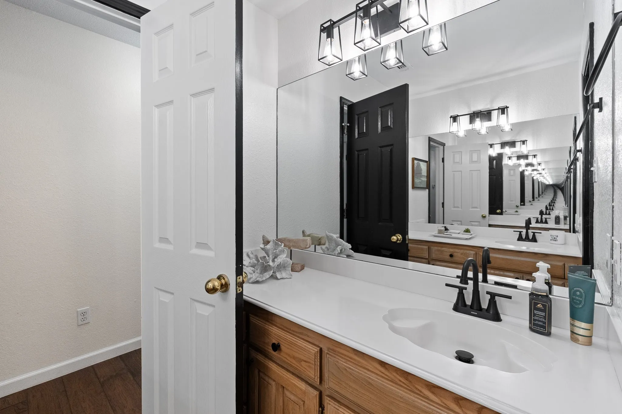 Vanity with a white countertop and integrated sink, wood-finish cabinetry, and a matte black faucet