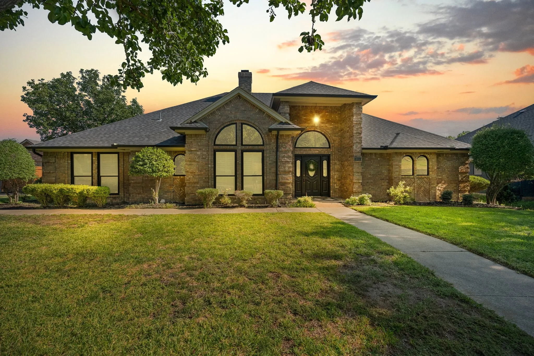 Stone facade with a dark wood entry door, multiple arched windows, and a paved walkway