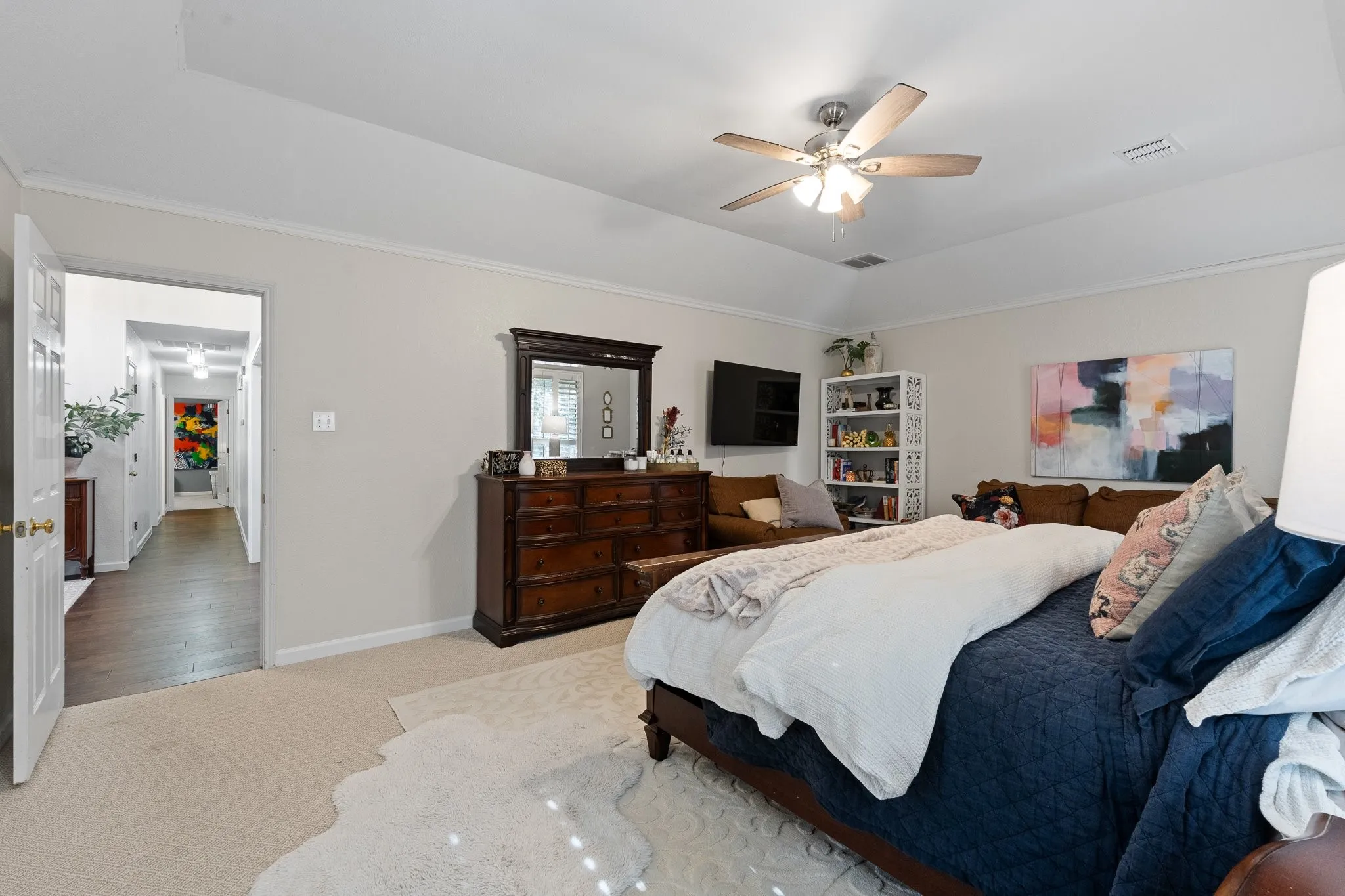Tray ceiling with a ceiling fan, light-colored carpeting, and crown molding