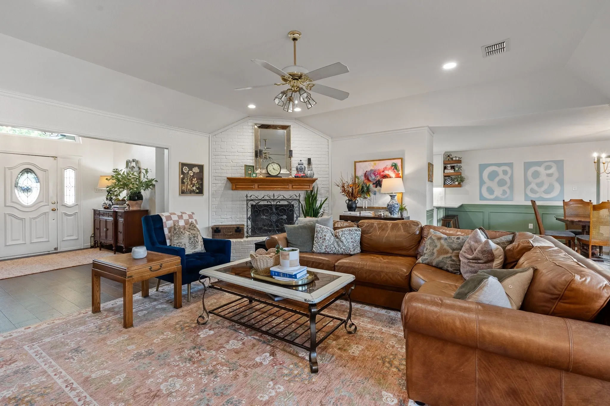 Vaulted ceiling, recessed lighting, ceiling fan, brick-clad fireplace with wood mantel, and wood flooring