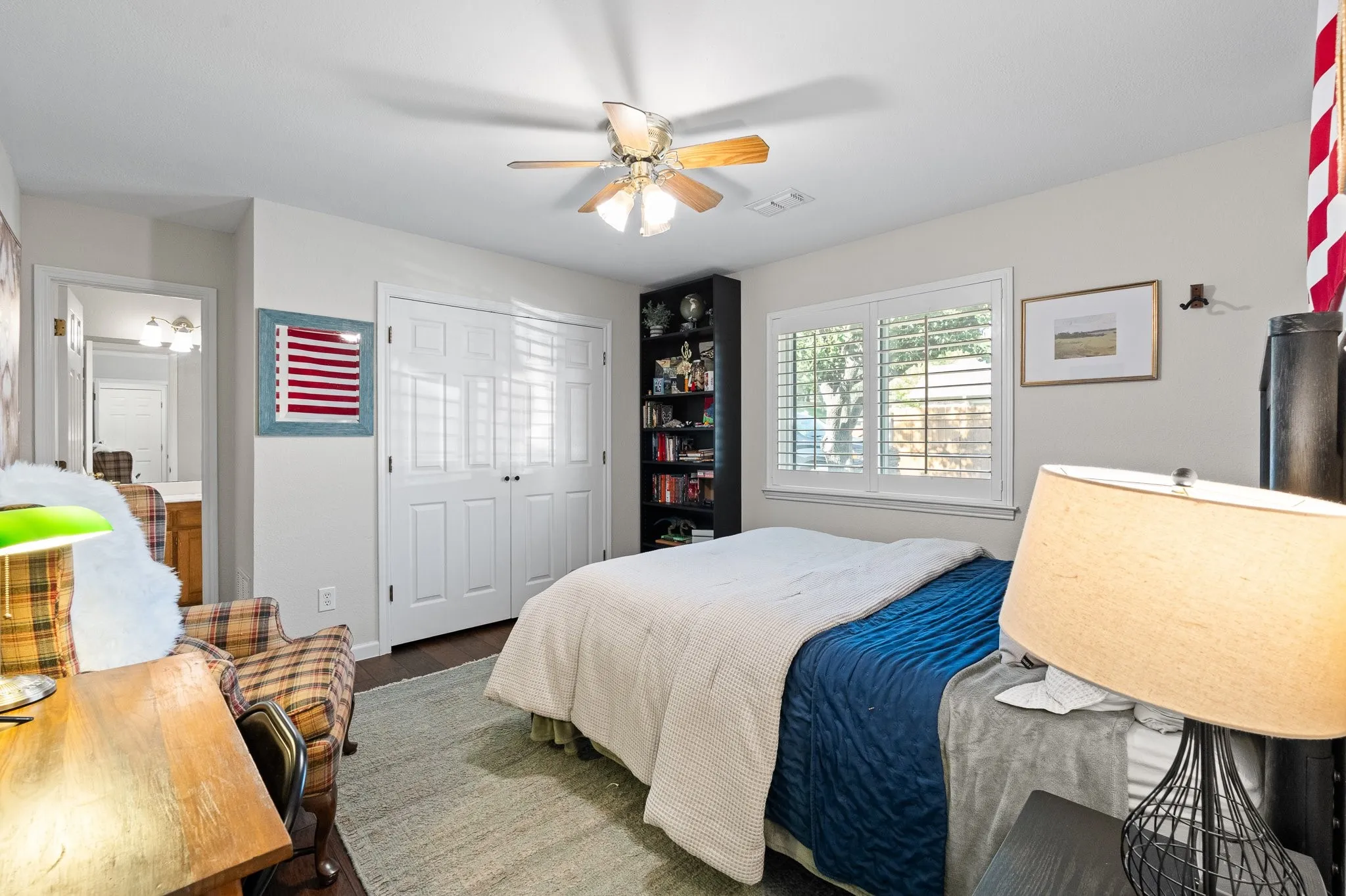 Ceiling fan, wood flooring, white plantation shutters, and a white paneled closet