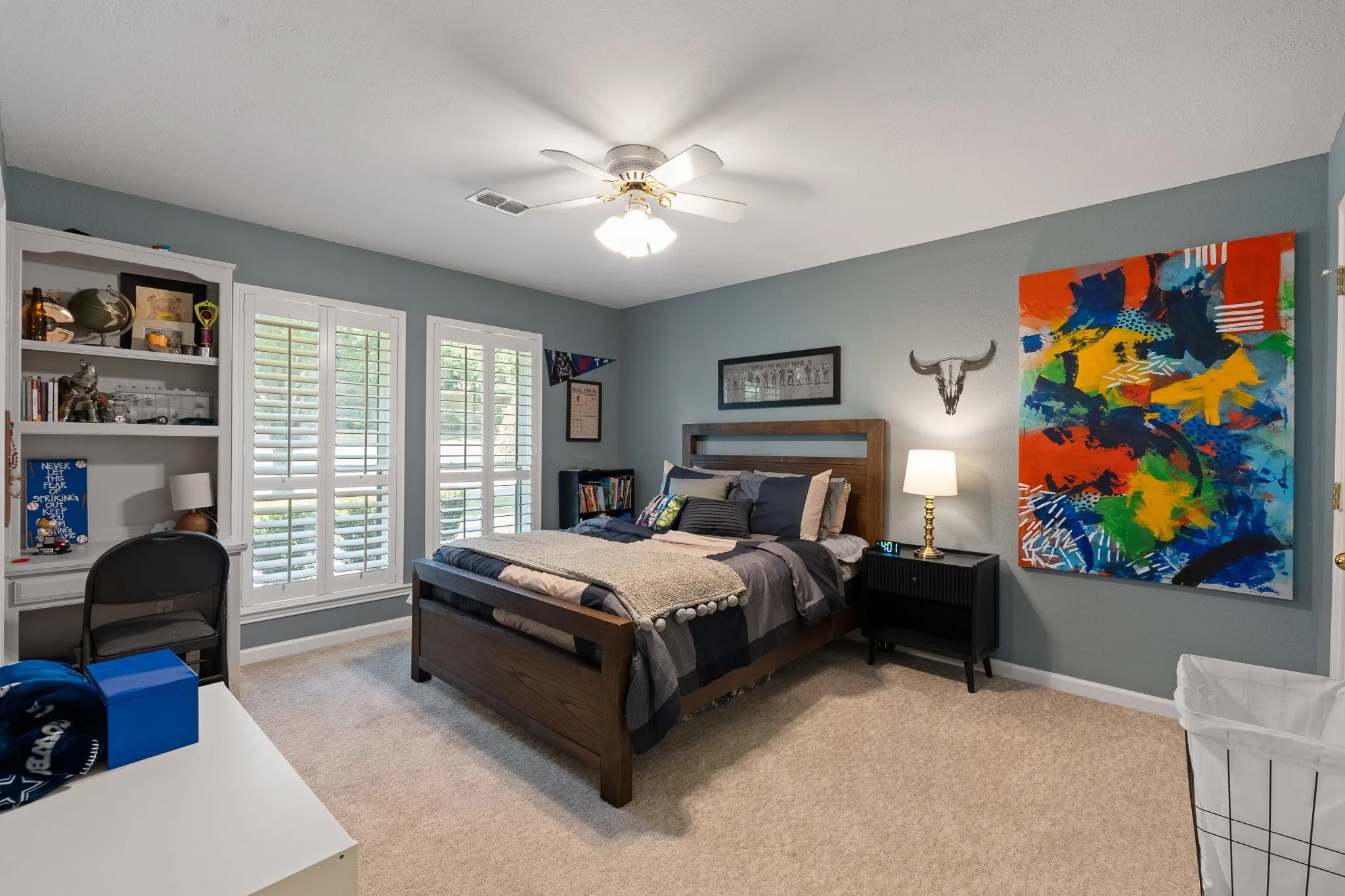 Carpeted flooring, white plantation shutters, built-in desk with shelving, and ceiling fan with integrated lighting