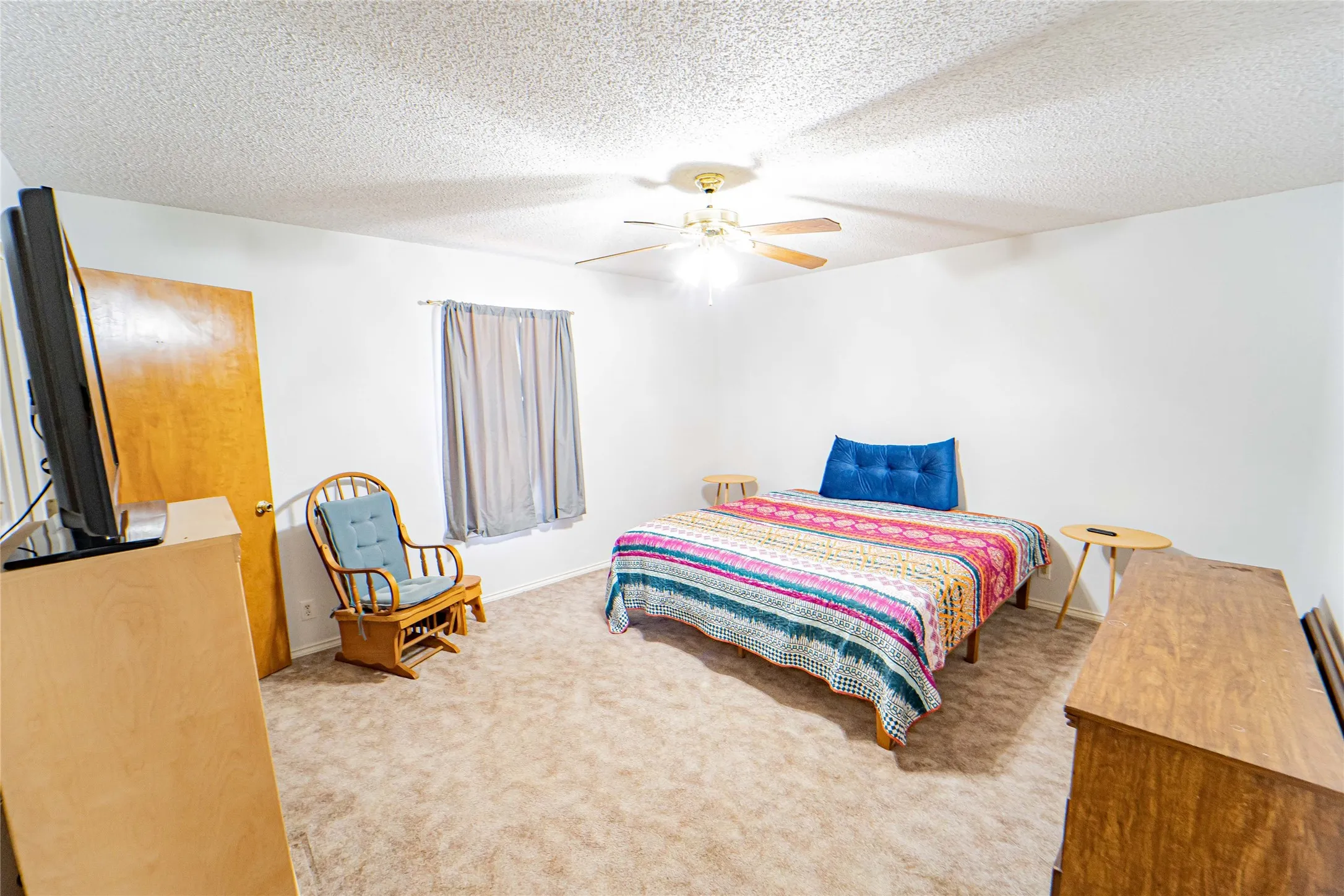Carpeted flooring, white painted walls, ceiling-mounted light fixture, and a window with blinds