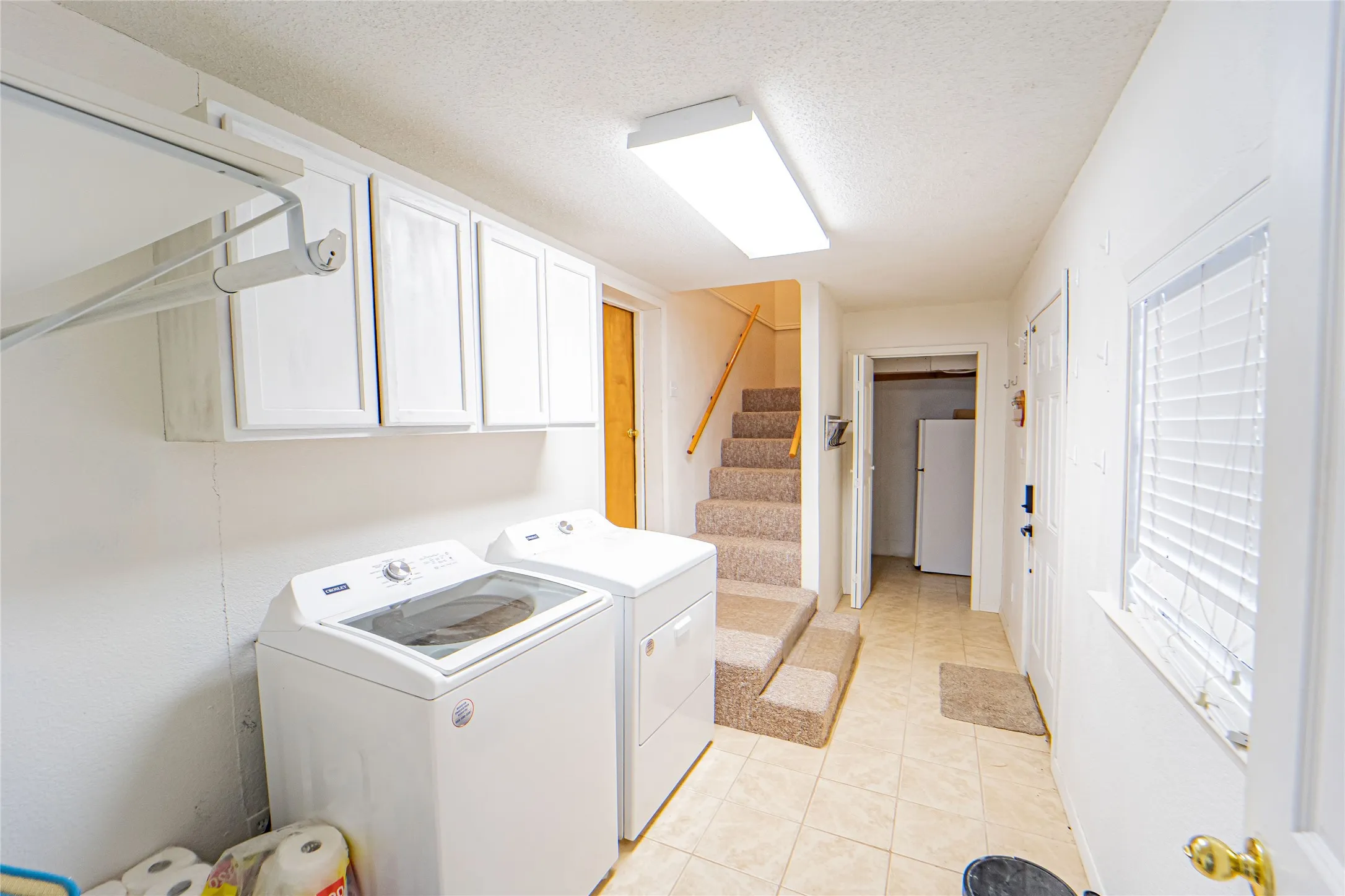 Utility area featuring tiled flooring, built-in cabinetry, and a window with blinds