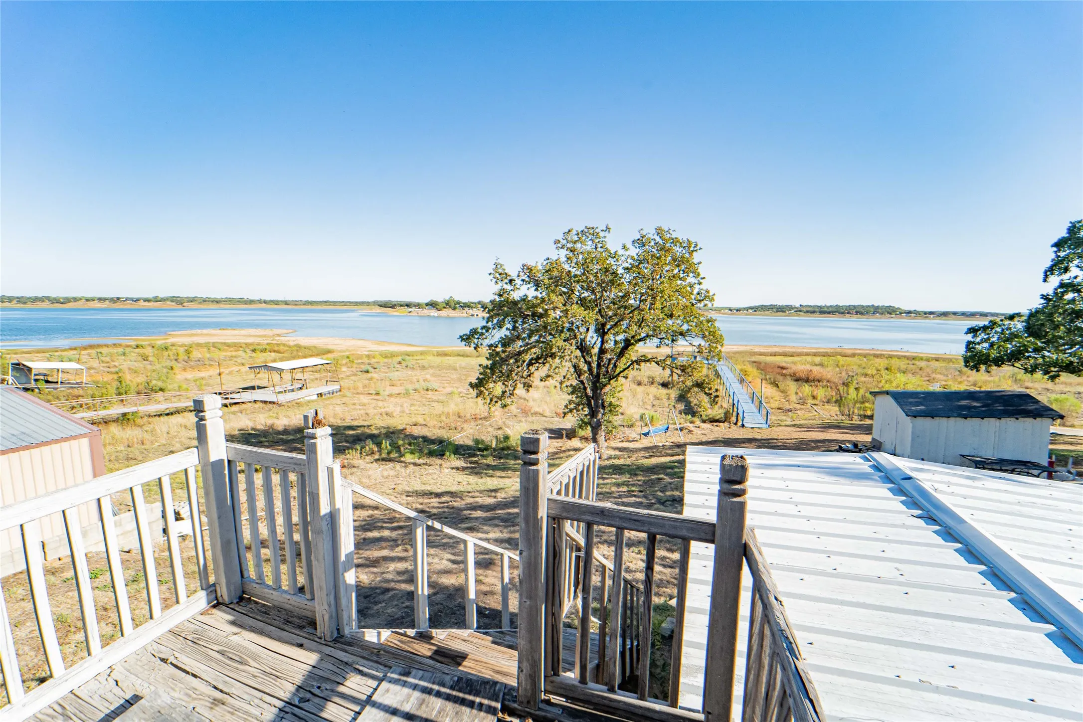 Waterfront property featuring a wood-plank deck, wood railing, and metal roof structure
