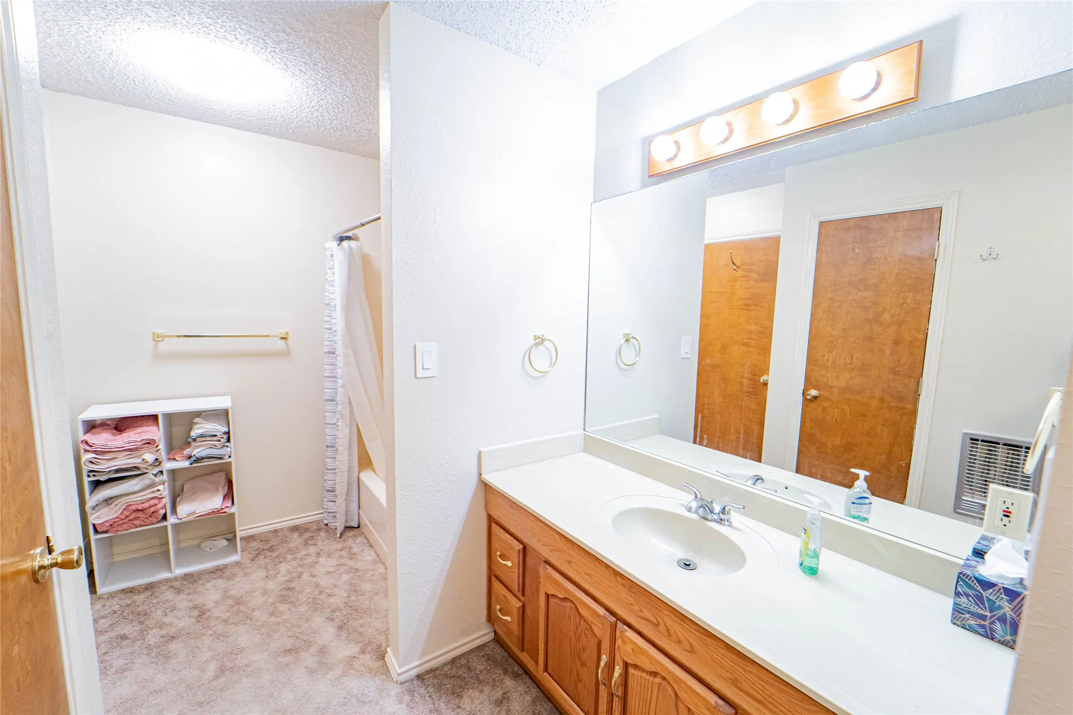 White vanity with integrated sink, wood-finish cabinetry, and a large wall-mounted mirror