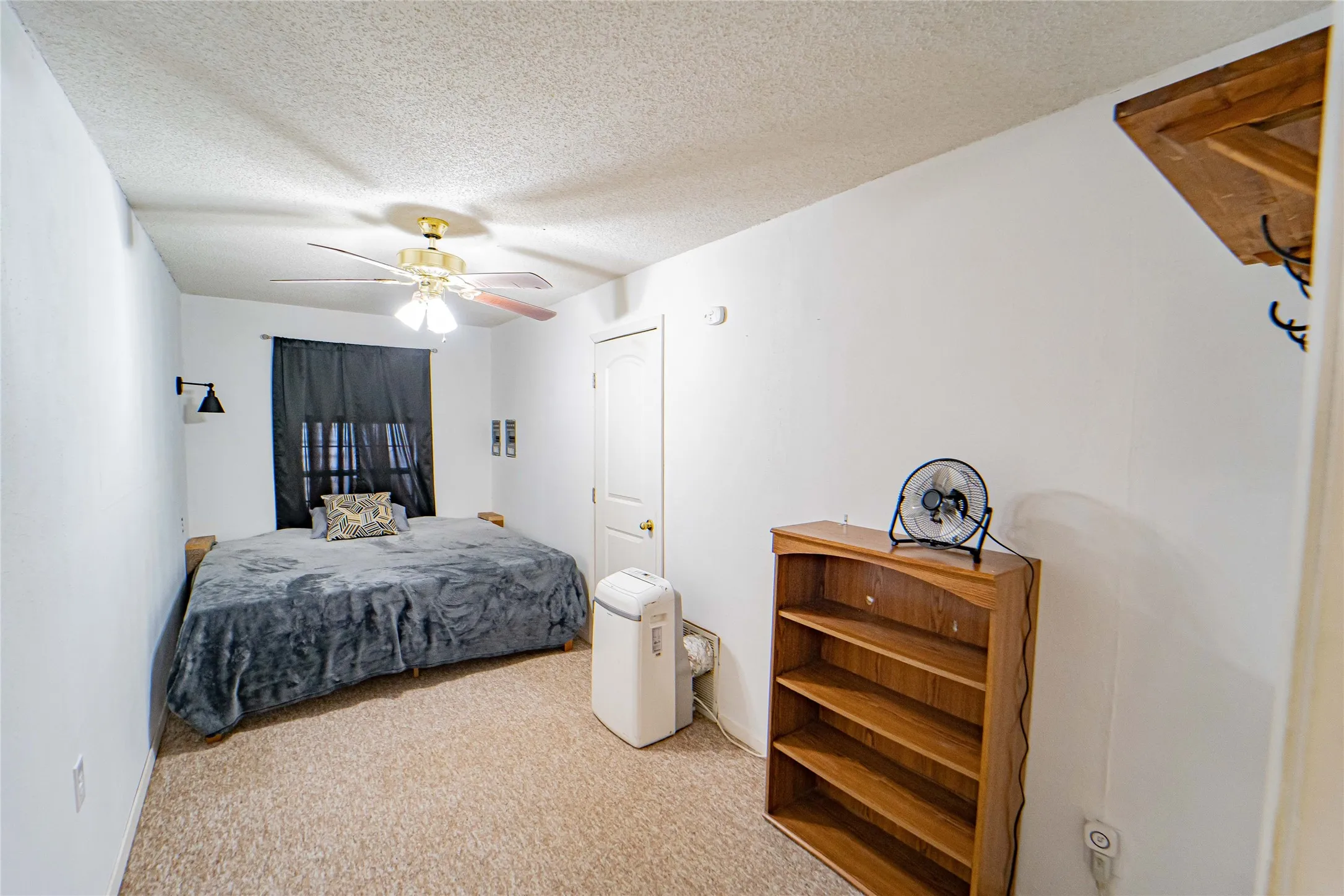 Carpeted room with a ceiling fan, sconce lighting, and white walls.