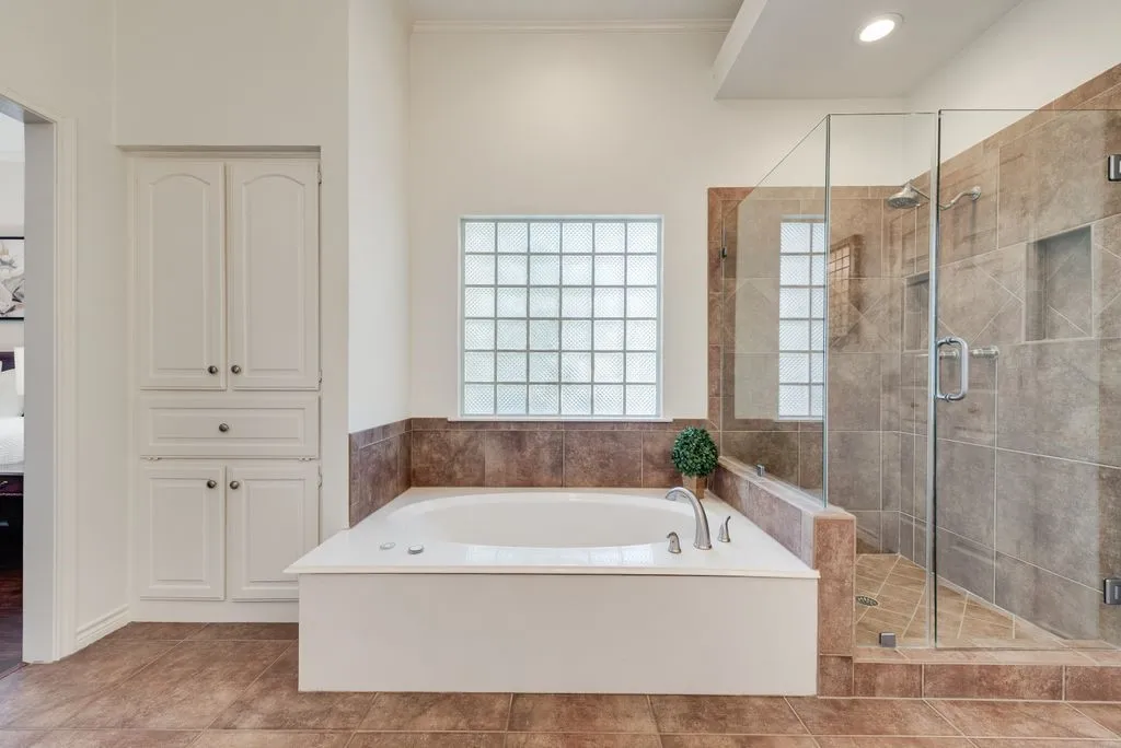 Primary suite includes large spa bath and glass enclosed glass shower, linen cabinet, two vanities, walk in closet.