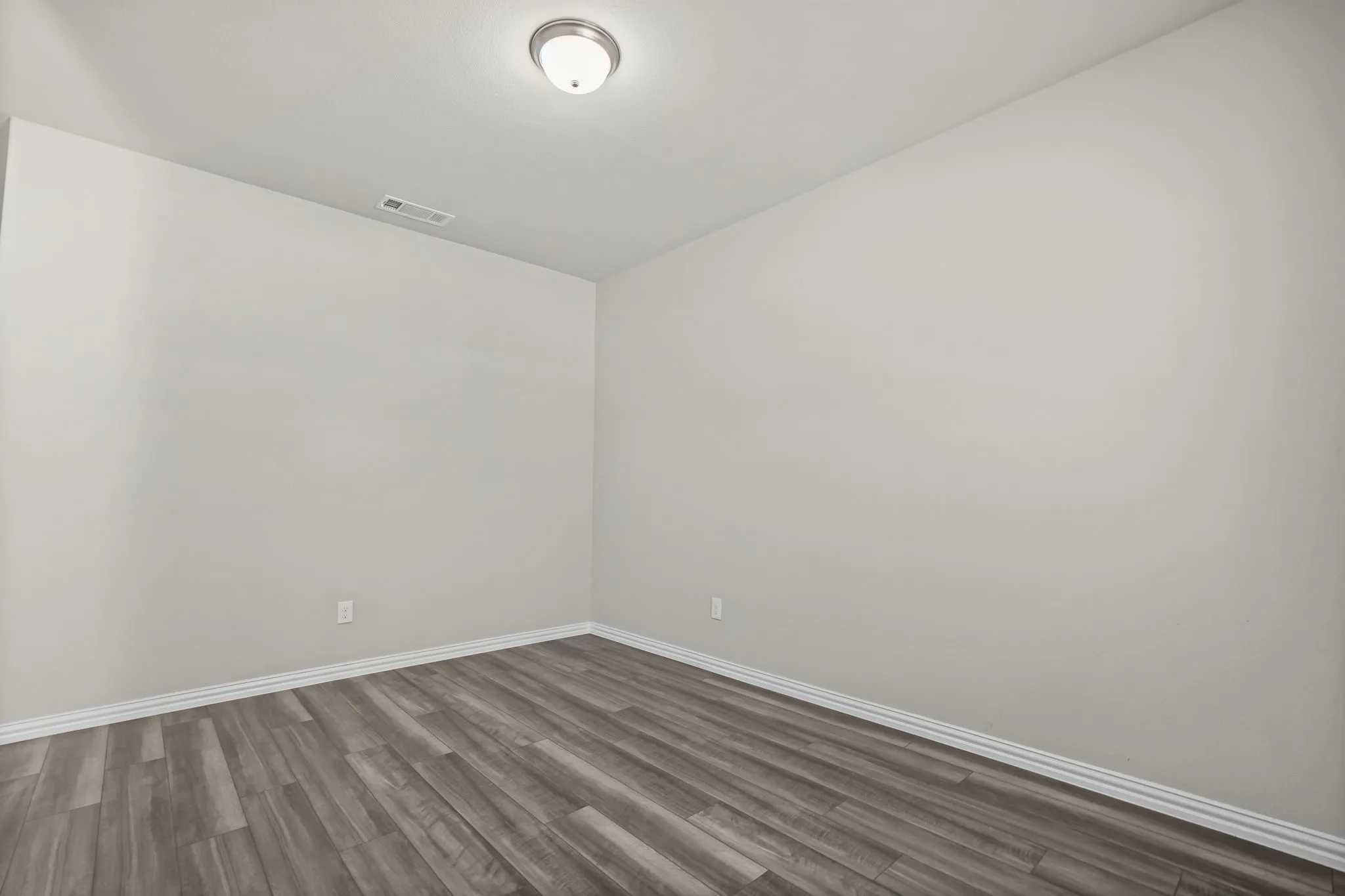 Neutral wall finishes, wood-finish flooring, and a flush-mount ceiling light