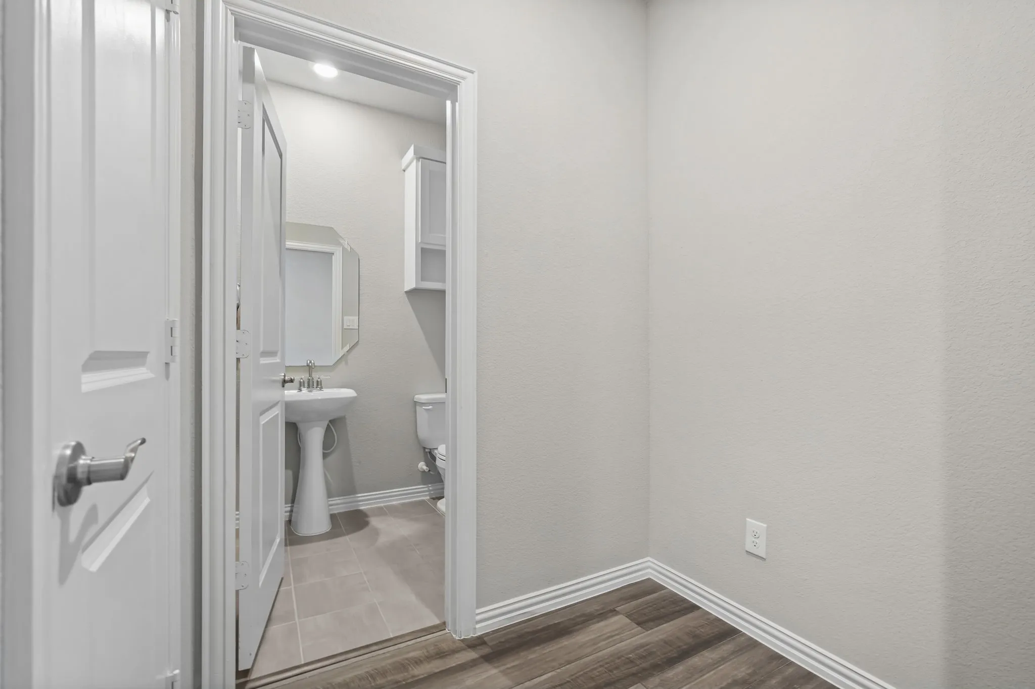 Wood-finish flooring with white trim and a neutral wall color