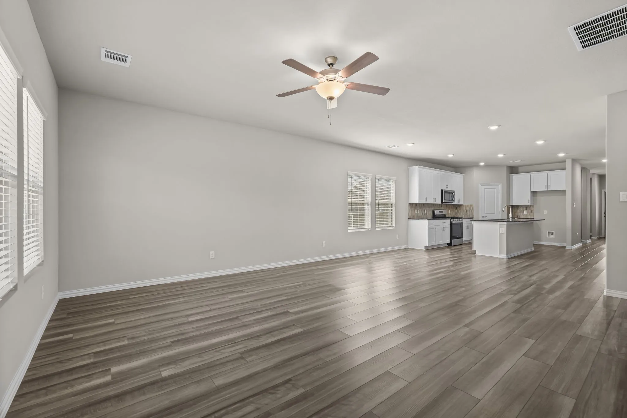 Open-concept living area with wood-finish flooring, white cabinetry, a kitchen island, and recessed lighting