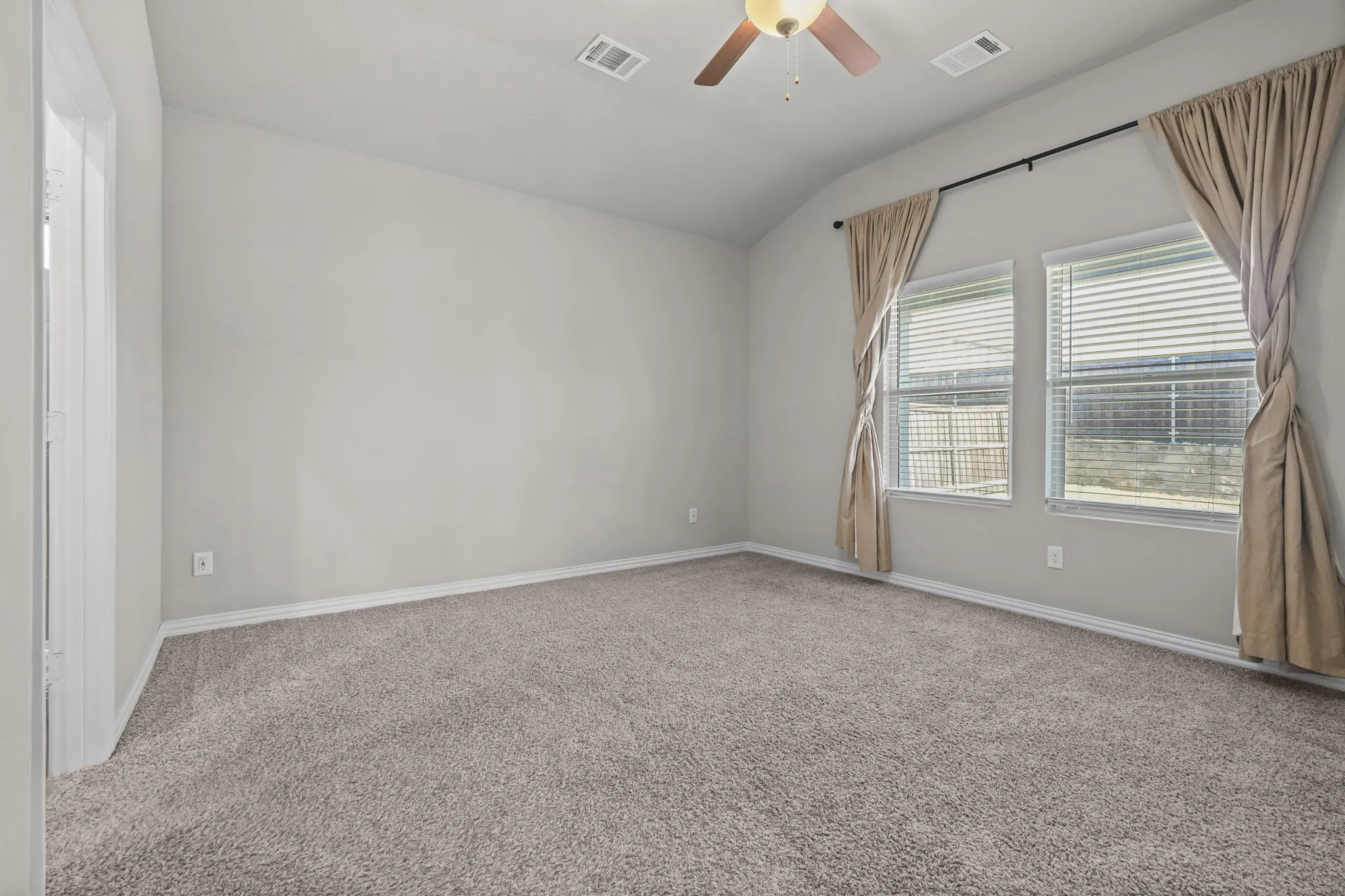High ceilings with a ceiling fan, neutral carpet flooring, two windows with blinds, and light-colored walls