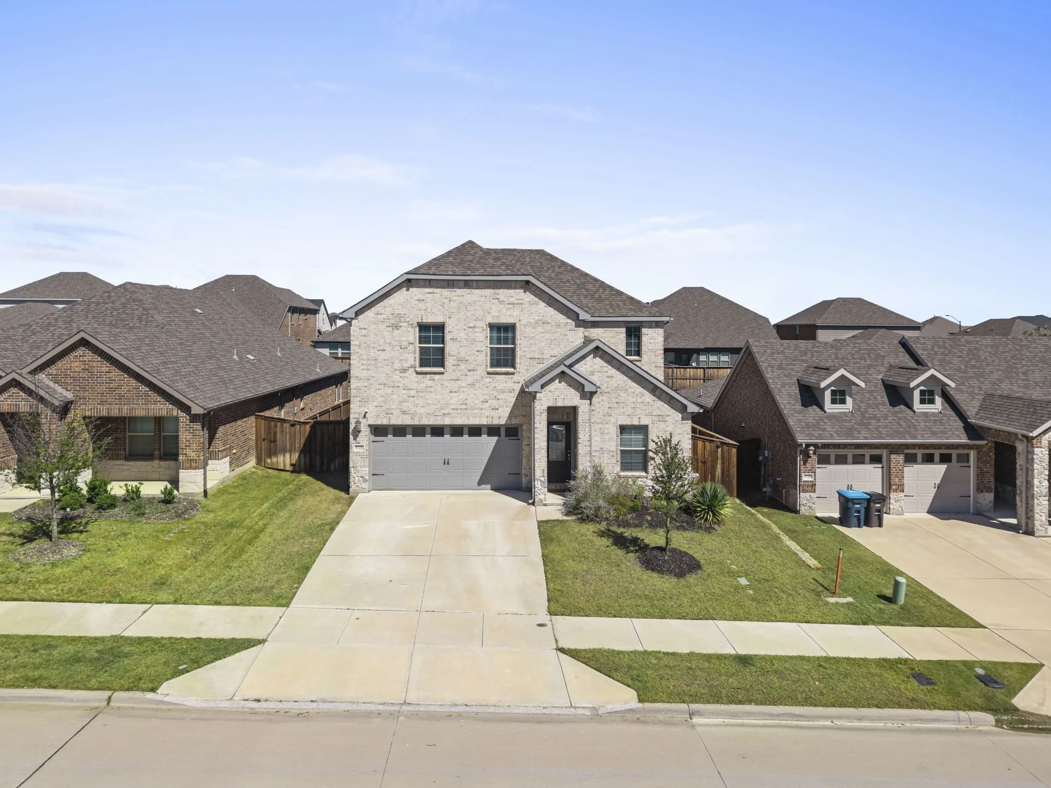 Brick exterior with stone accents, attached two-car garage, and a concrete driveway