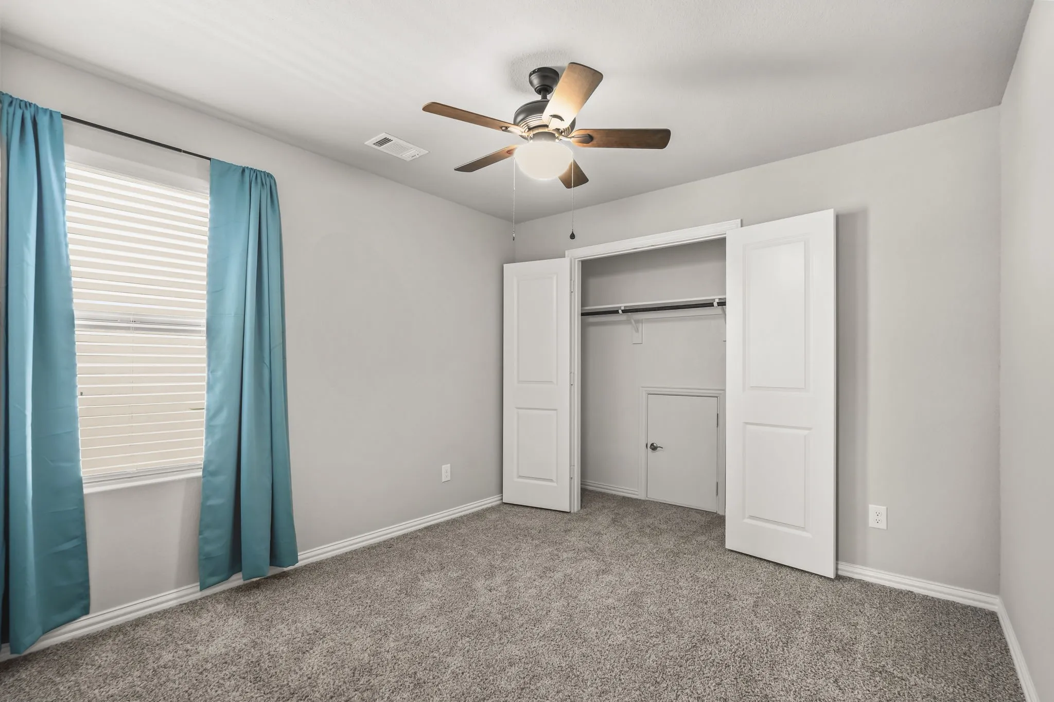 Carpeted flooring, a window with horizontal blinds, a ceiling fan with integrated lighting, and a bi-fold door closet with built-in shelving