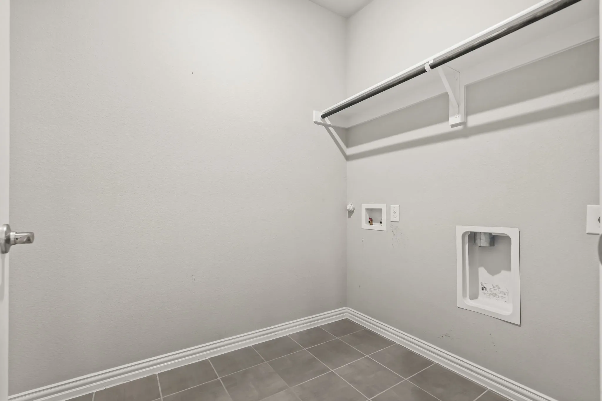 Utility room with tiled flooring and a built-in hanging rod