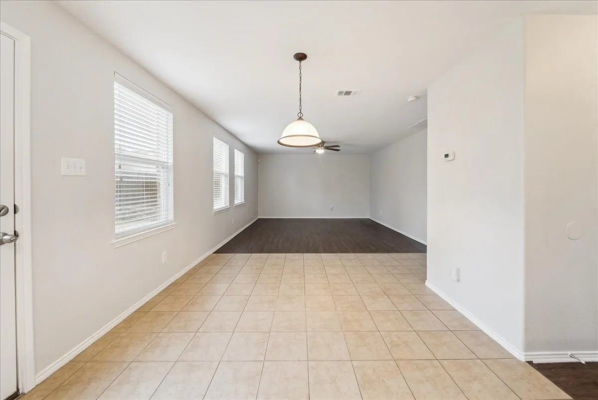 Expansive open-concept living area featuring ceramic tile flooring, wood-finish flooring, multiple windows with blinds, and a built-in ceiling fan