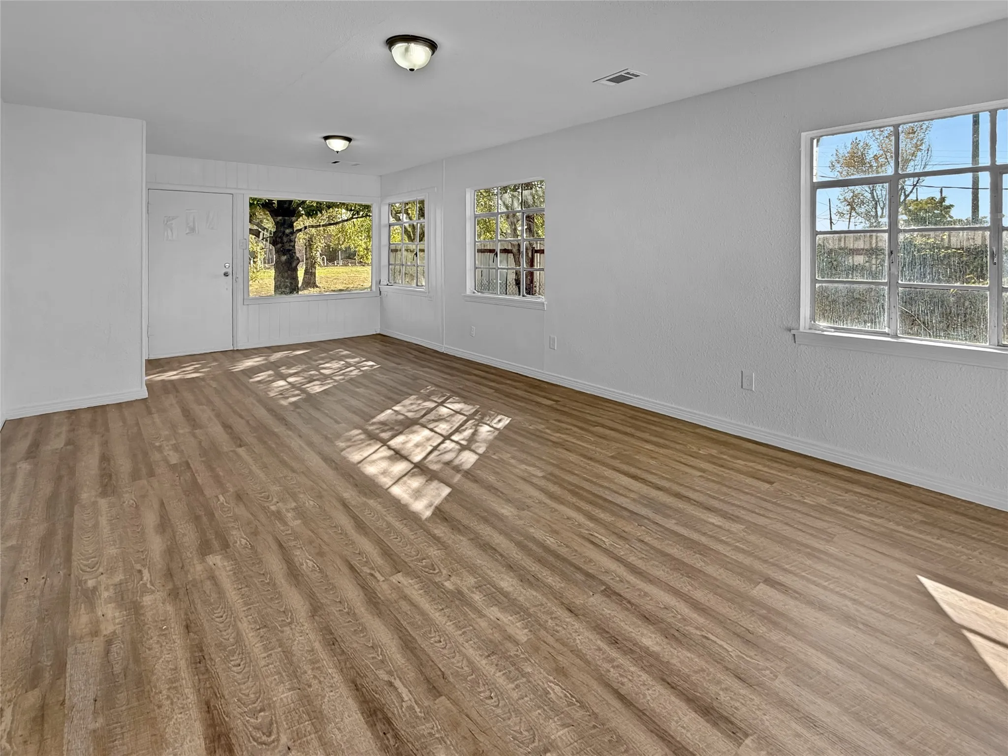 Wood-finish flooring throughout, multiple windows, and flush-mount ceiling lights