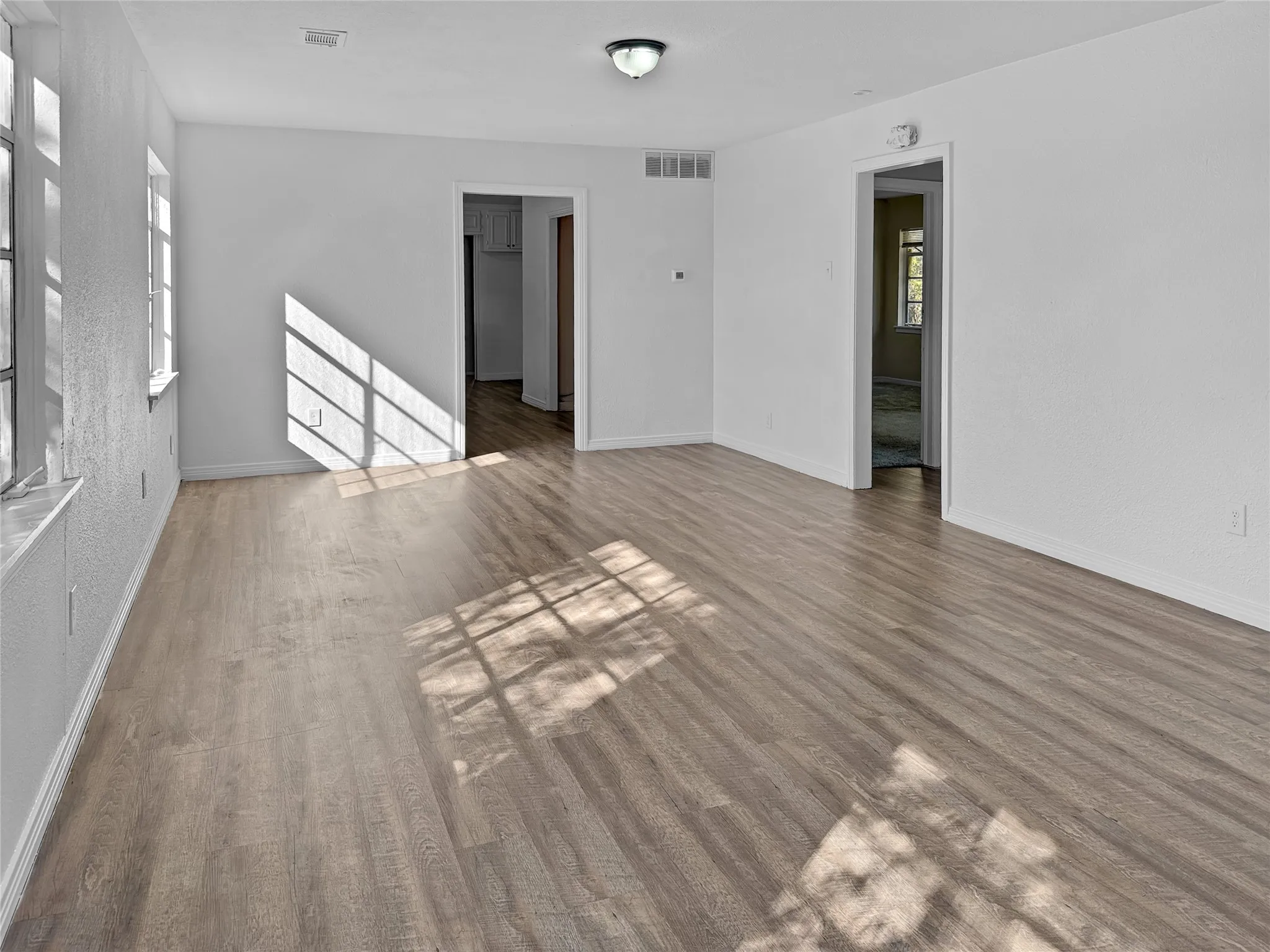 Wood-finish flooring, multiple windows, and a flush mount light fixture