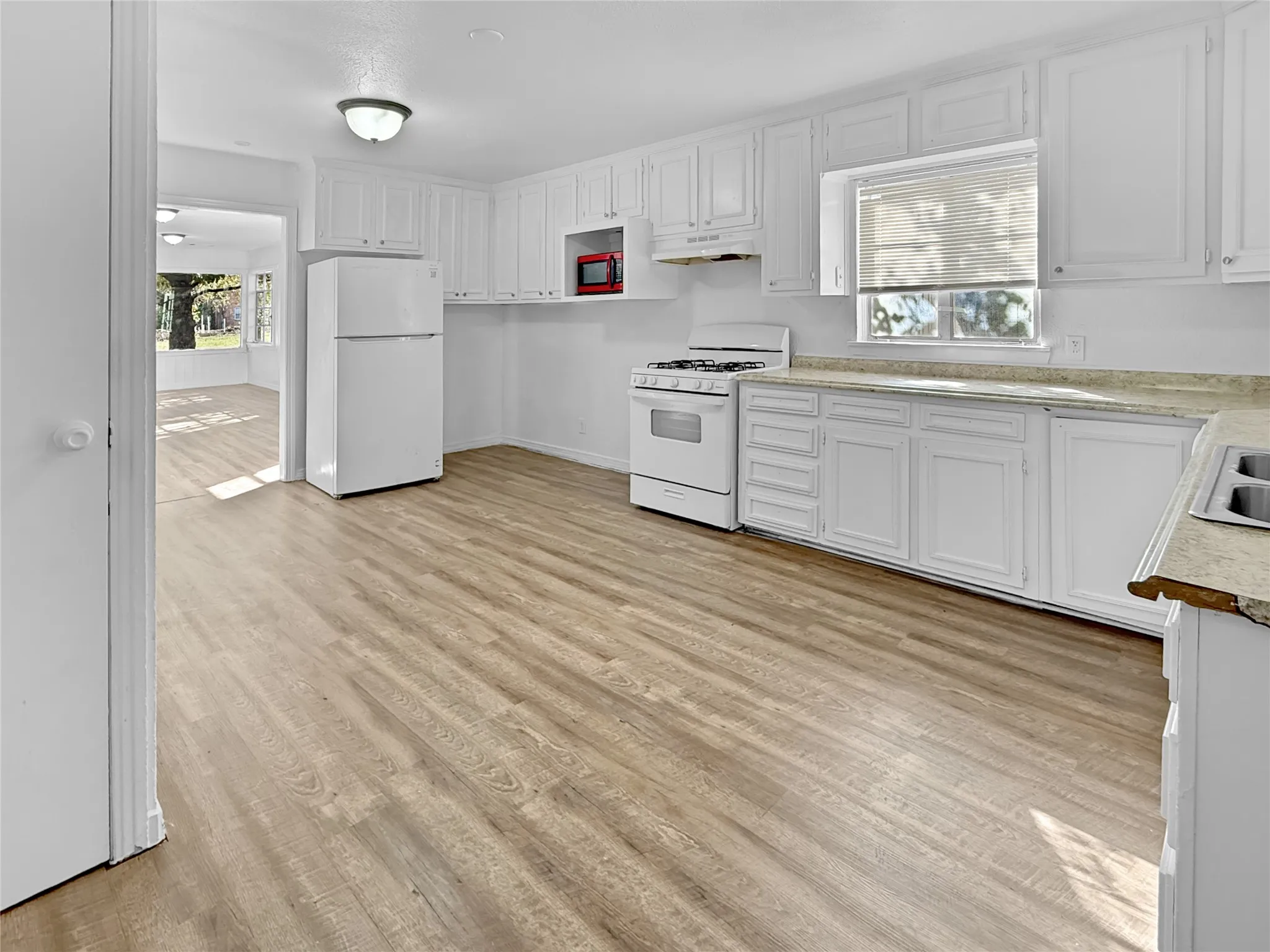 Kitchen with wood-finish flooring, white cabinetry, a gas range, and a double basin sink