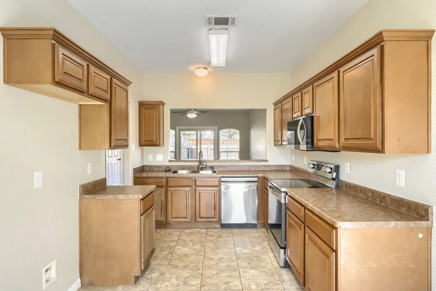 Kitchen featuring extensive cabinetry, laminate countertops, a stainless steel dishwasher, an electric range, and an over-range microwave