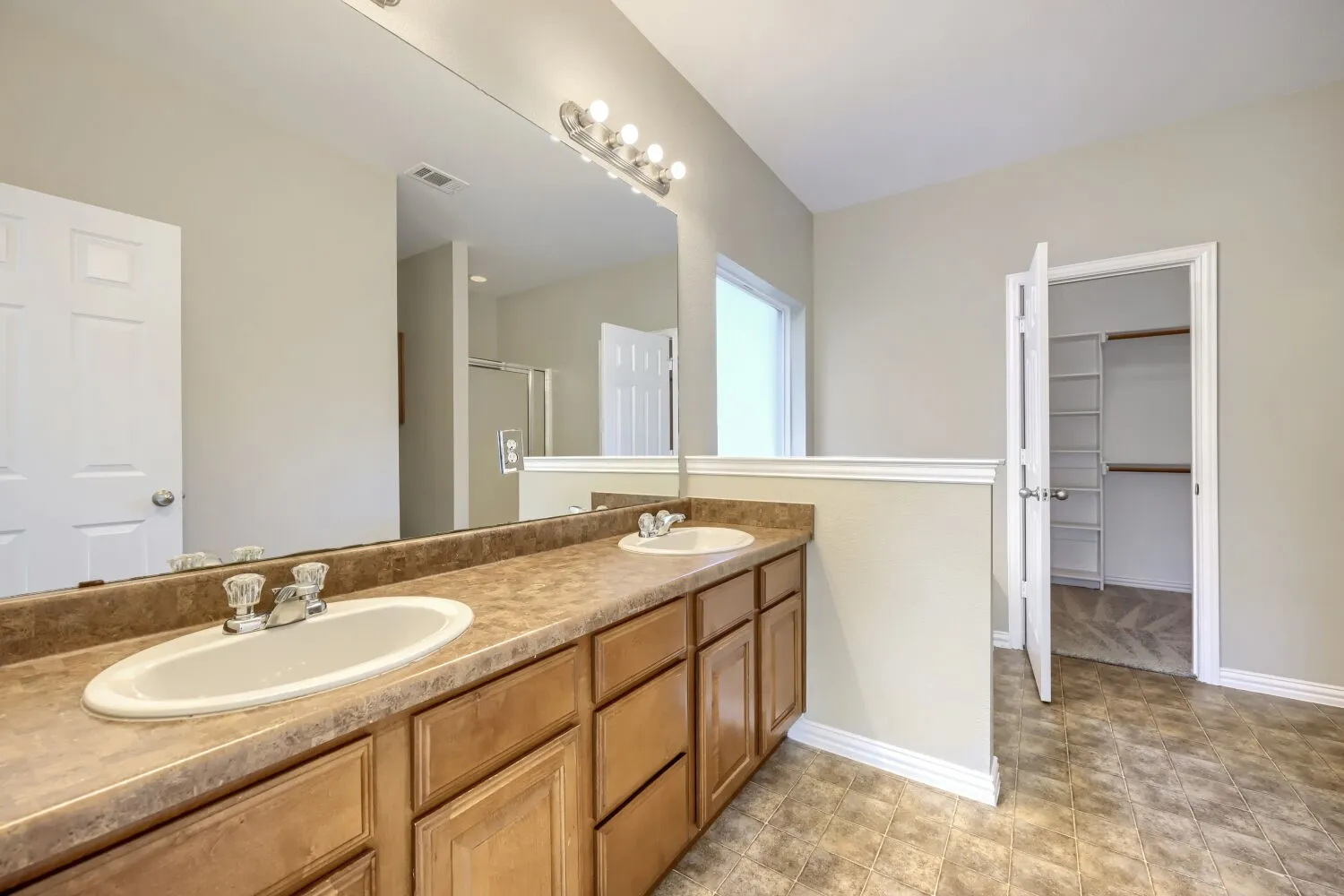 Dual vanity with integrated sinks, wood-finish cabinetry, and a full-width mirror