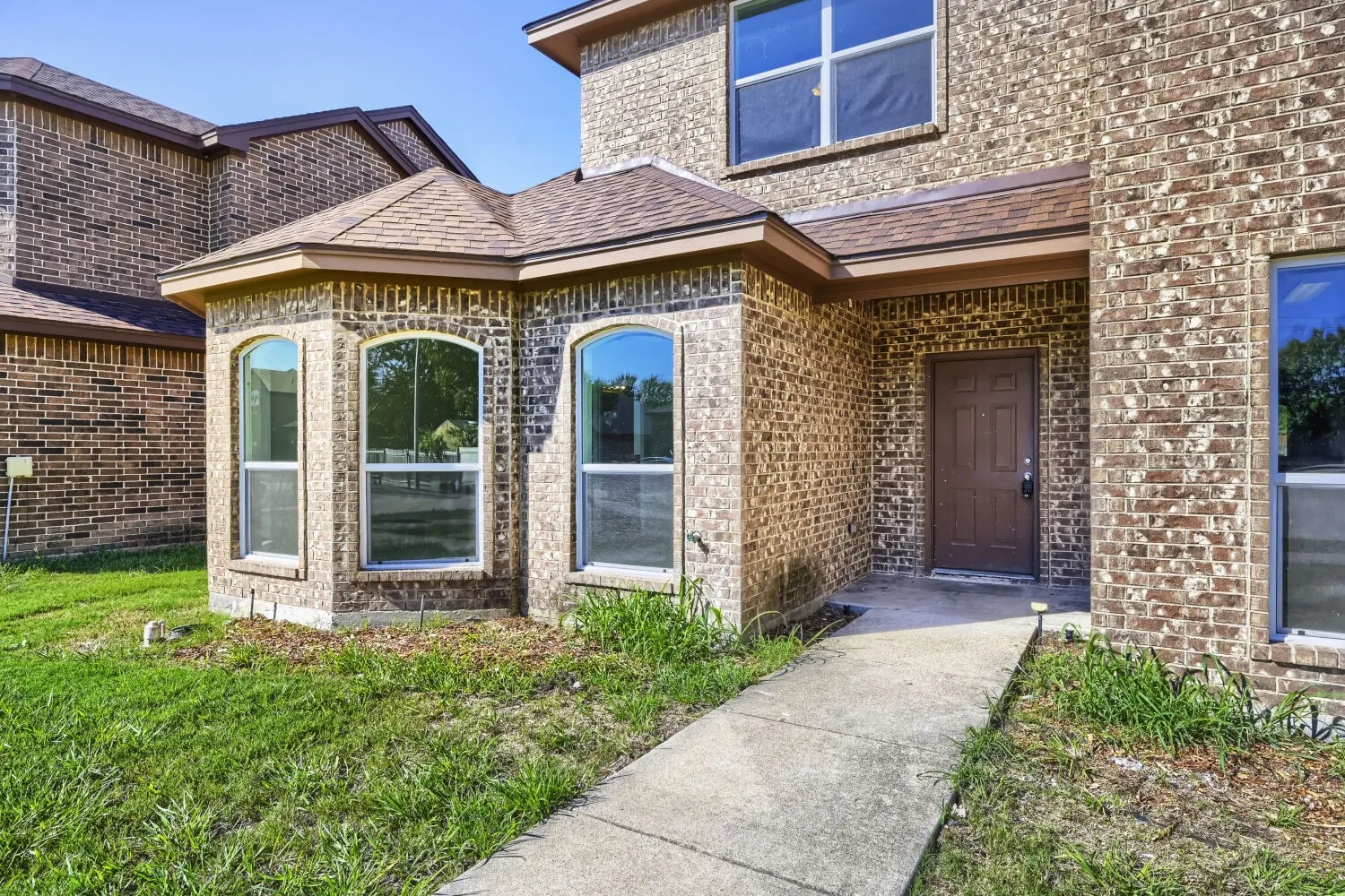Brick exterior with a prominent entry, covered porch, and arched windows