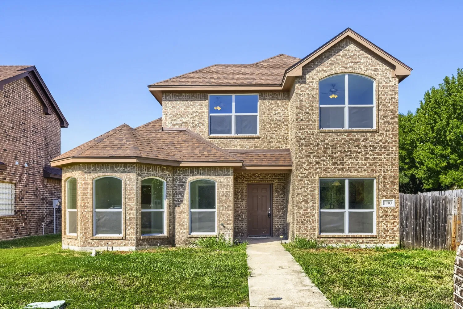 Brick exterior with an arched window, a bay window, and a brown front door