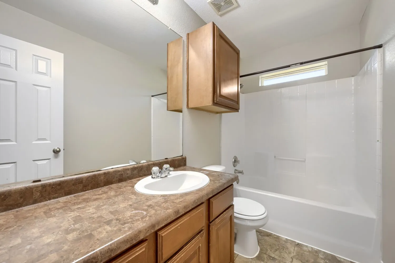 Vanity with integrated sink, wood-finish cabinetry, and a full-width mirror
