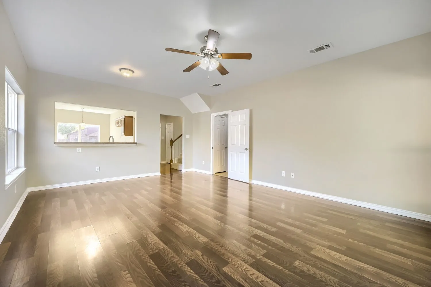 Wood-finish flooring throughout, vaulted ceiling, and a ceiling fan with integrated lighting