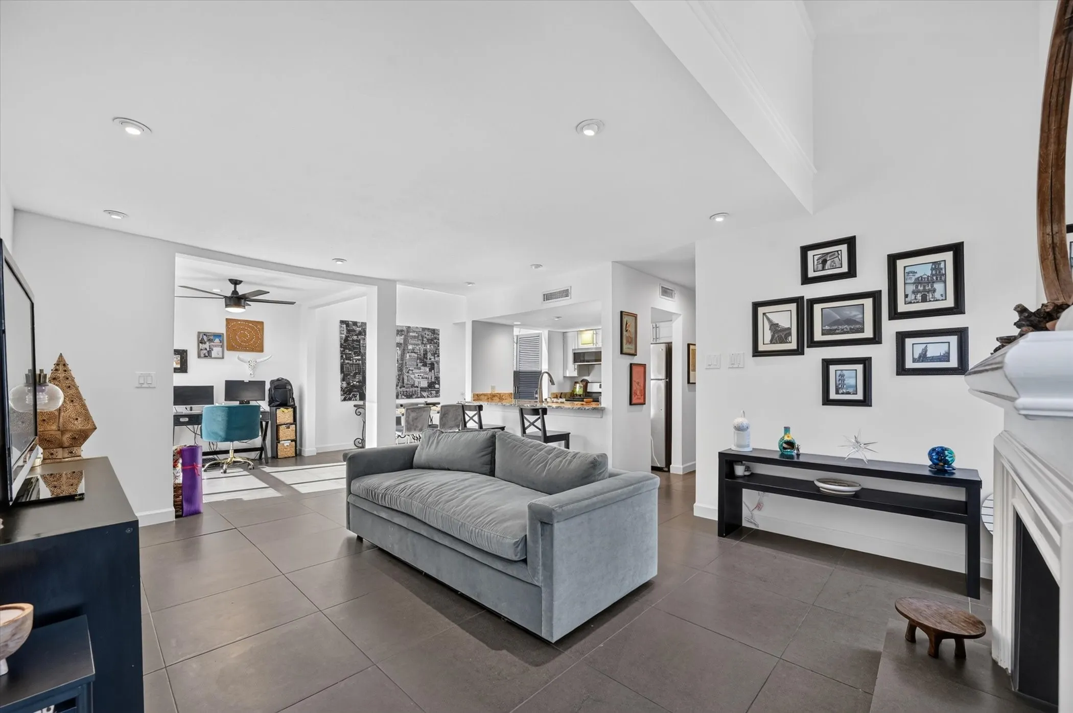 Spacious living area featuring large format tile flooring, recessed lighting, and a white mantel