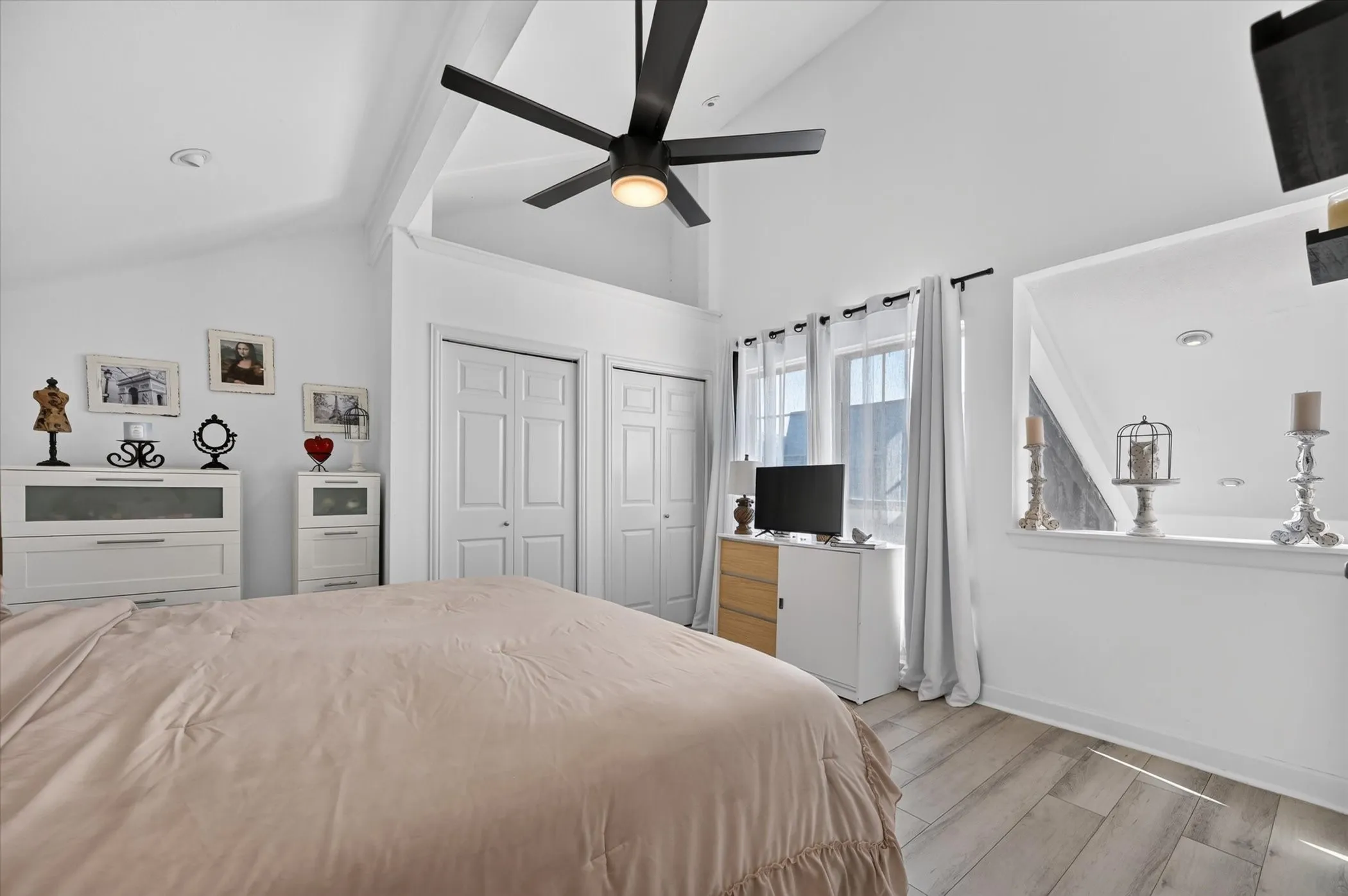 Vaulted ceiling with exposed beams, wood-finish flooring, and white trim