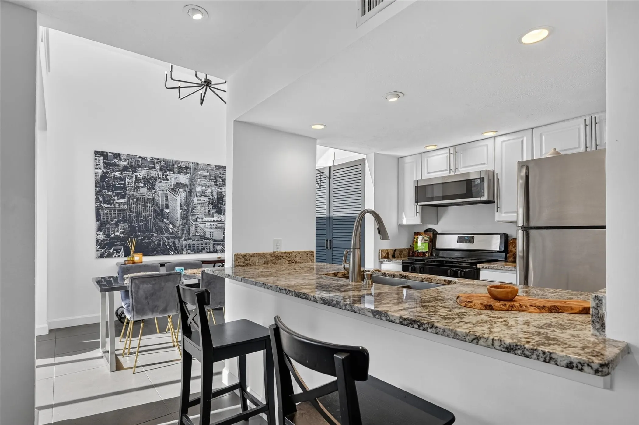 Kitchen featuring a granite countertop, undermount sink with a gooseneck faucet, stainless steel appliances, and white cabinetry