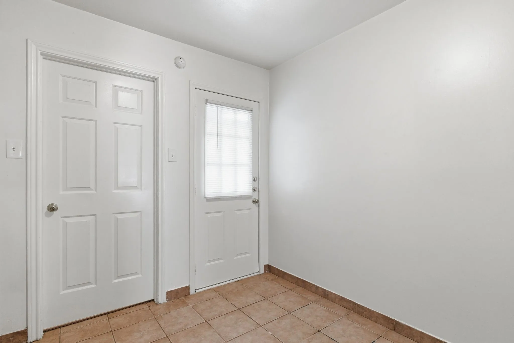 Neutral wall paint, tiled flooring, and multiple panel doors