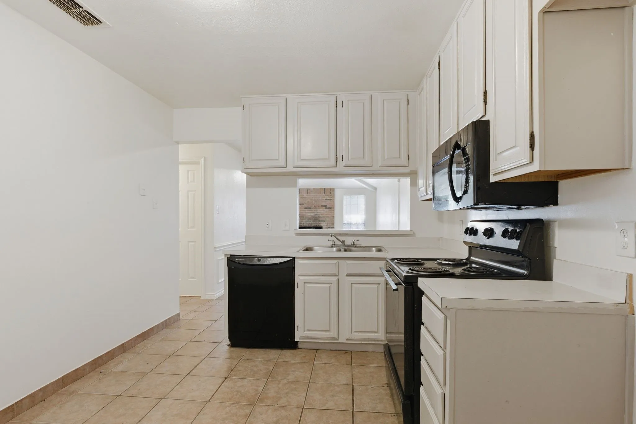 White cabinetry with black hardware, white countertops, stainless steel double basin sink, black built-in microwave, and black range