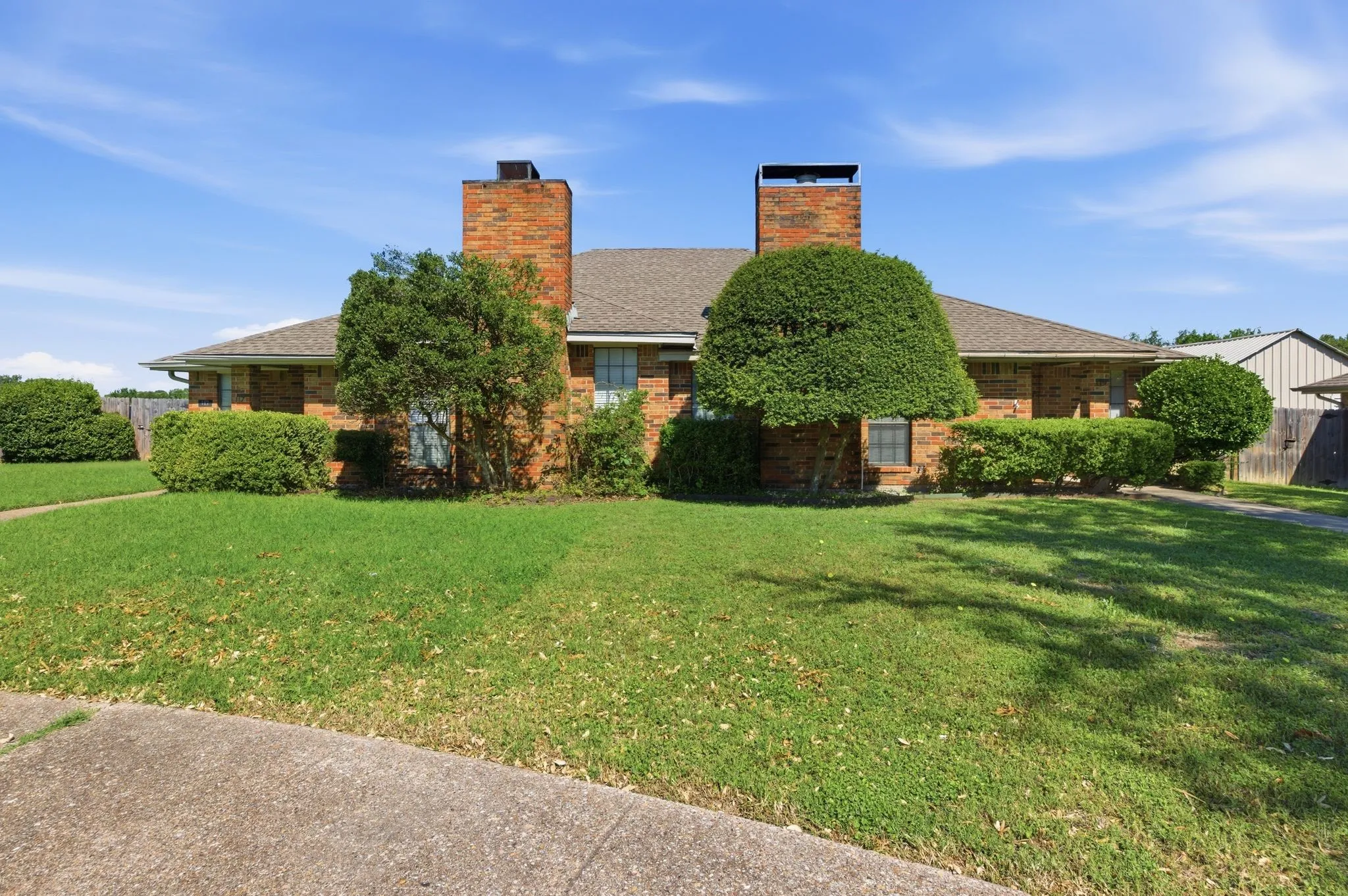 Brick exterior with two prominent brick chimneys and a gabled roof