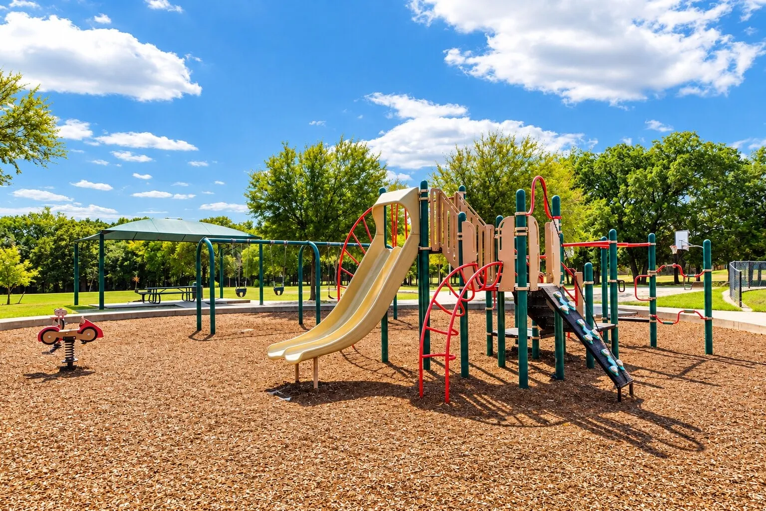 Recreational playground featuring a slide, swings, and climbing structures on a wood chip surface
