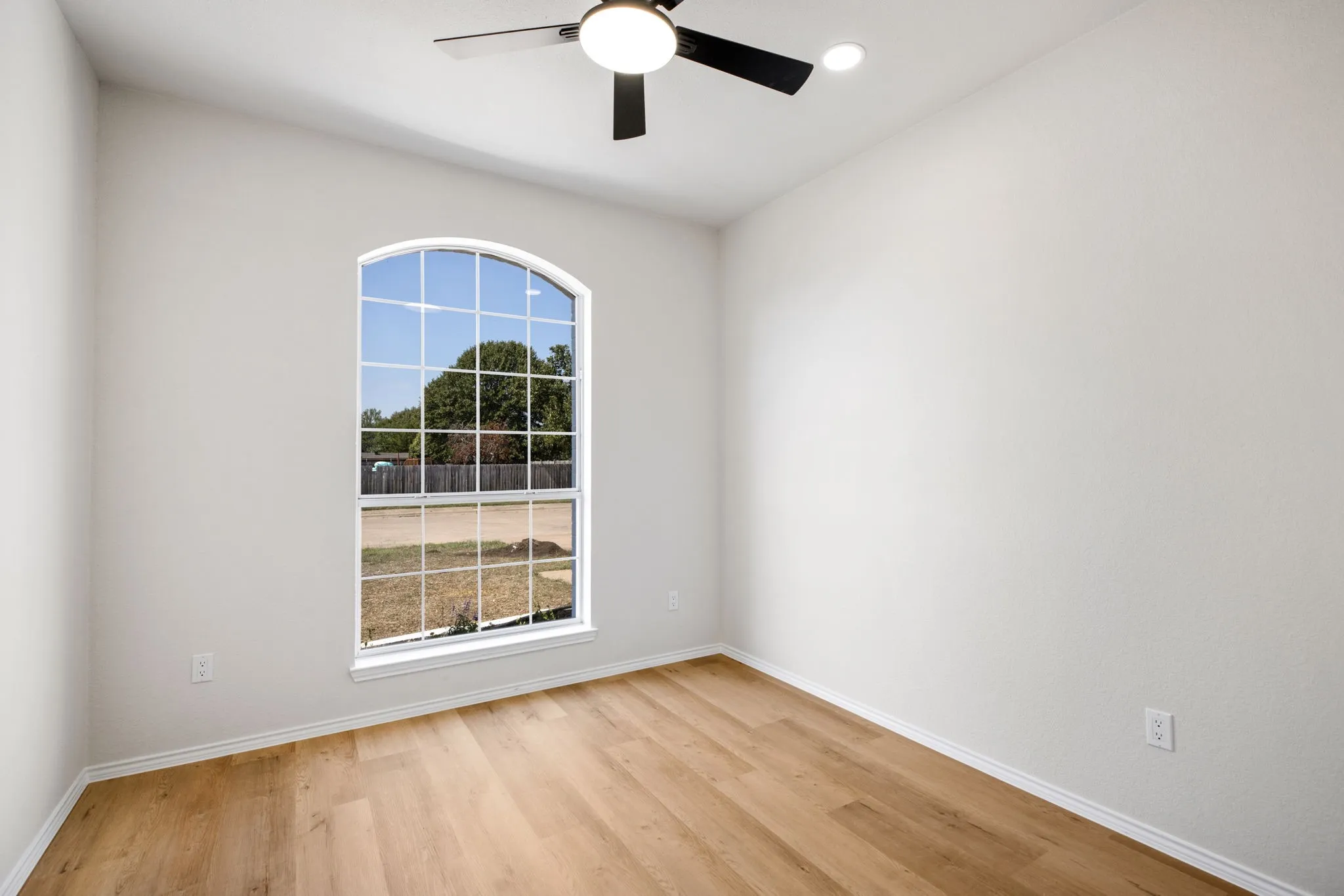 Wood-finish flooring, arched window, recessed ceiling light, and ceiling fan