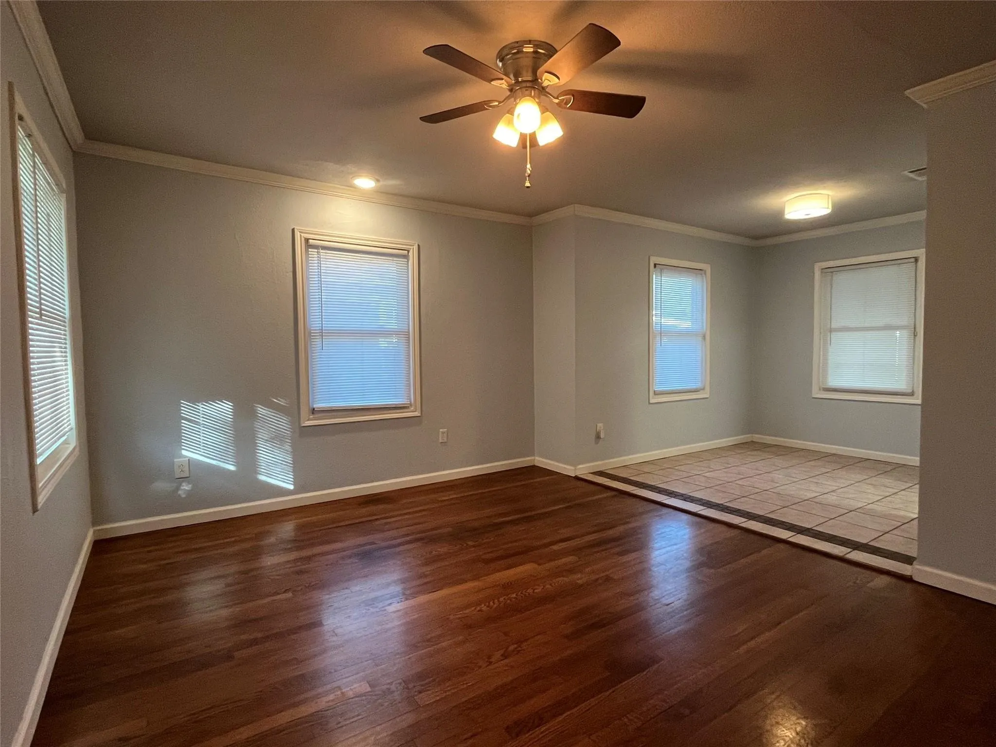 Hardwood flooring, light gray wall paint, multiple windows, ceiling fan, recessed lighting