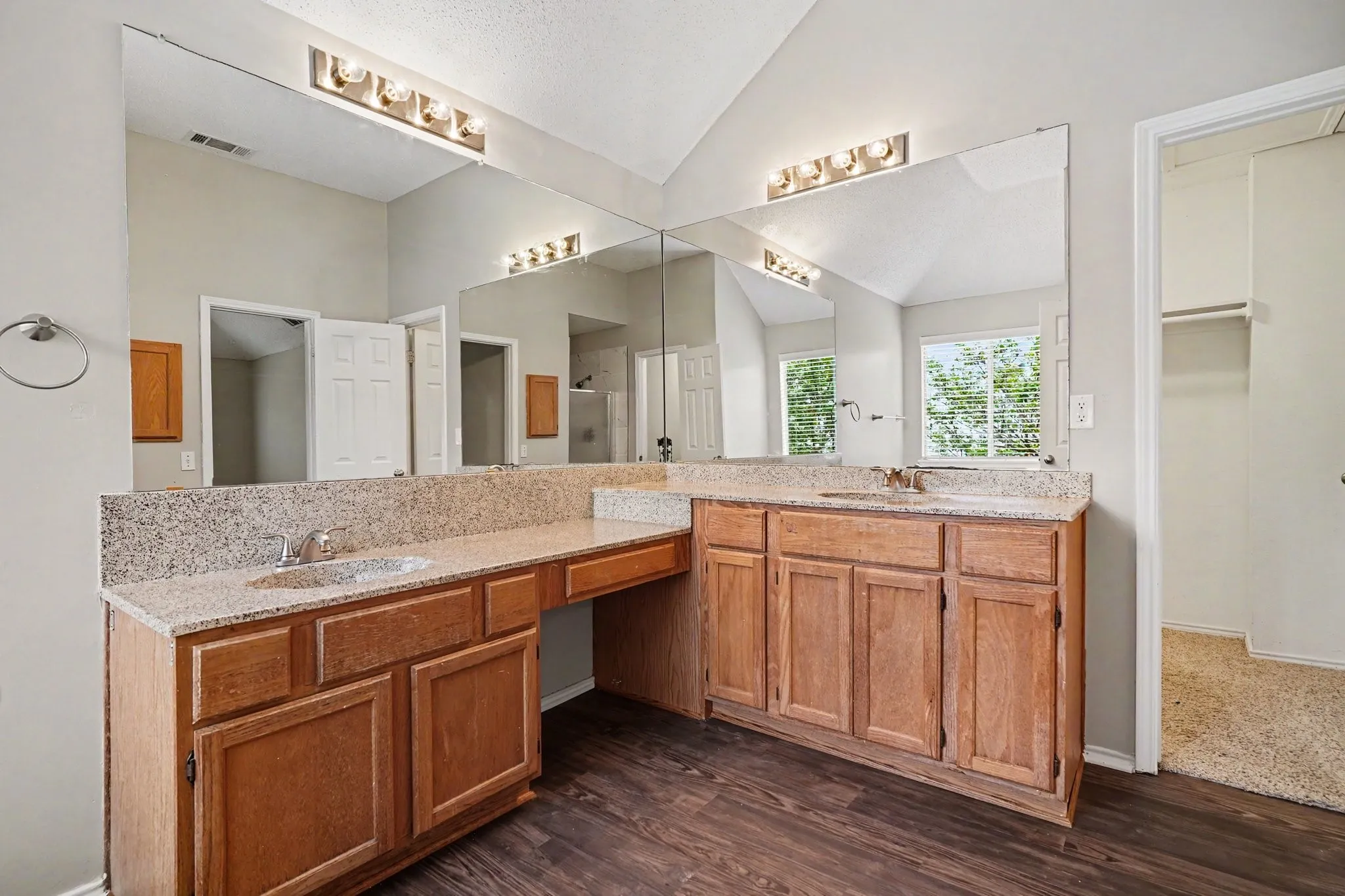 Primary bathroom offers corner vanity with dual sinks and a a powder area, walk in closet