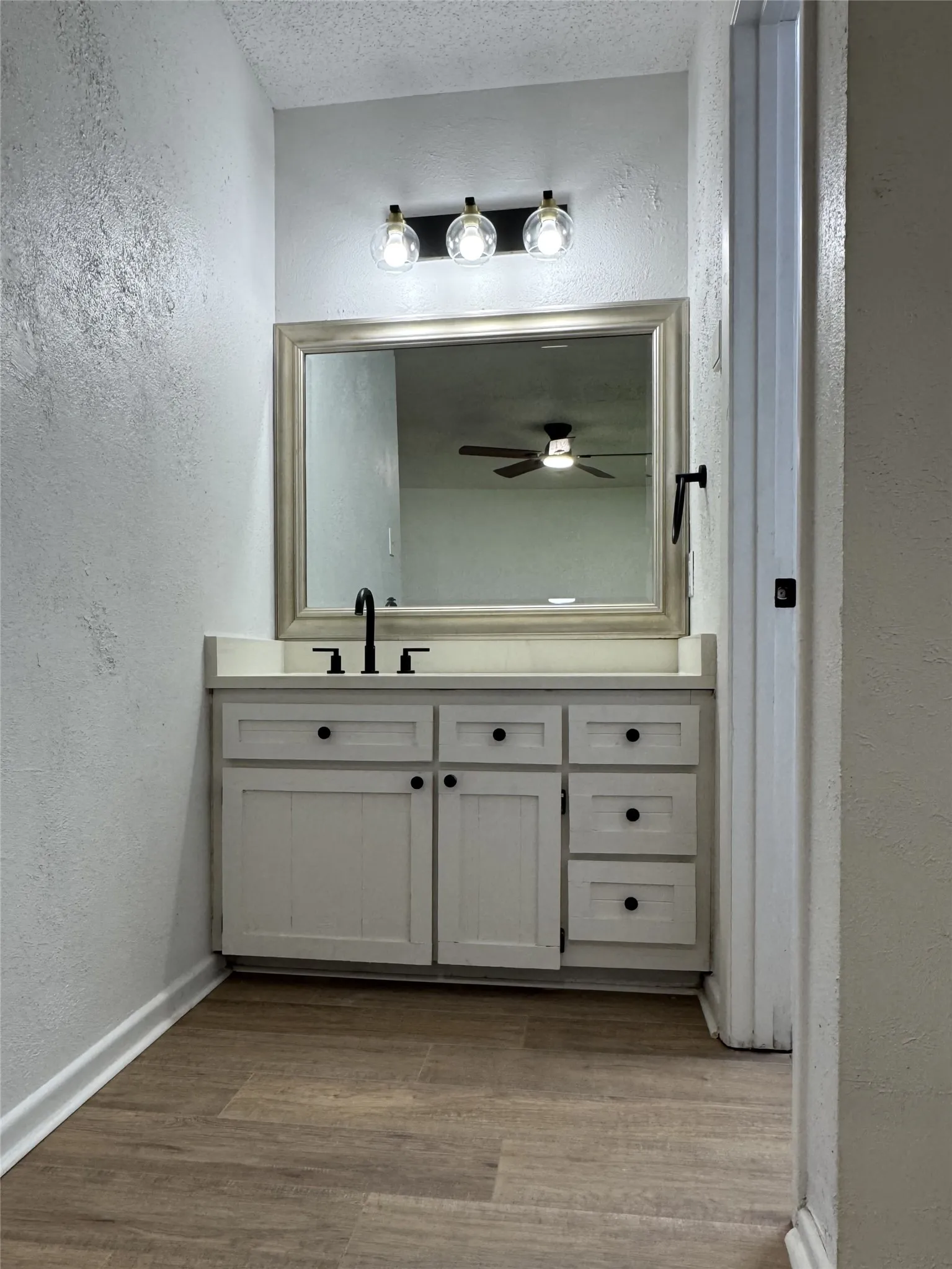 Vanity with matte black fixtures, framed mirror, and built-in cabinetry with black hardware